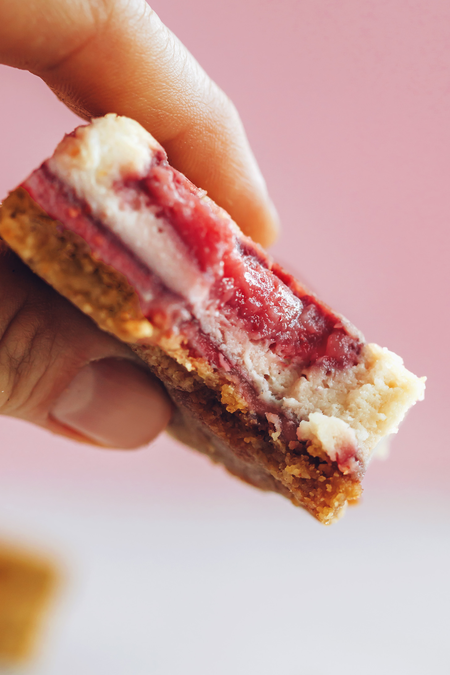 Holding up a strawberry cheesecake bar to show the texture