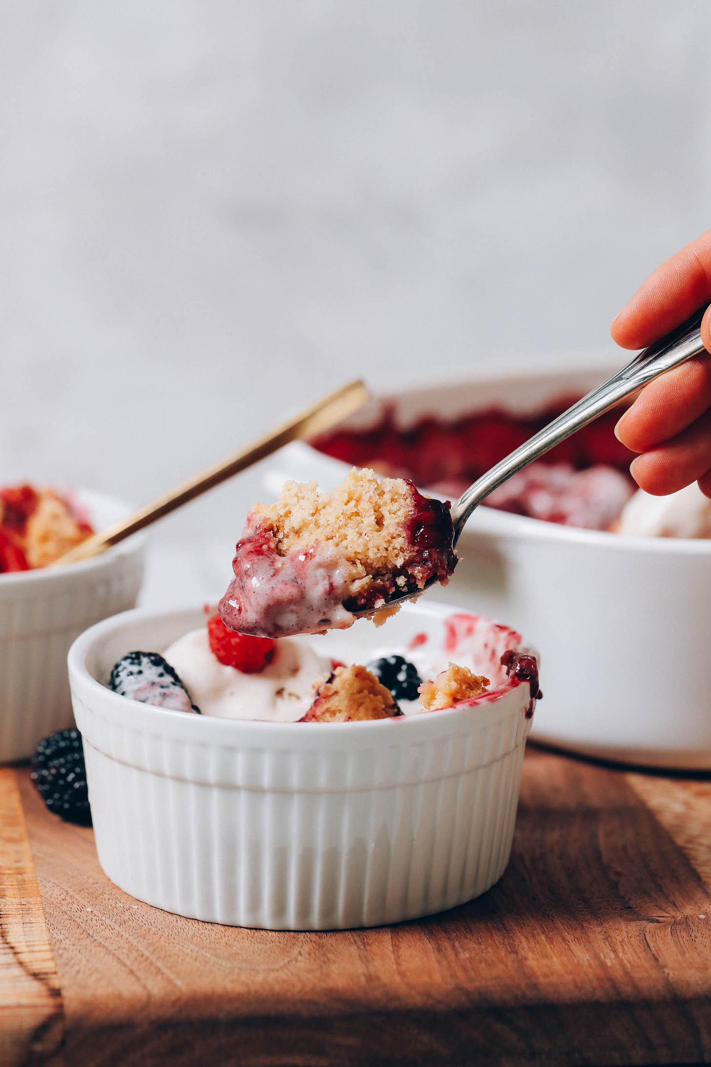Picking up a bite of berry cobbler from a bowl