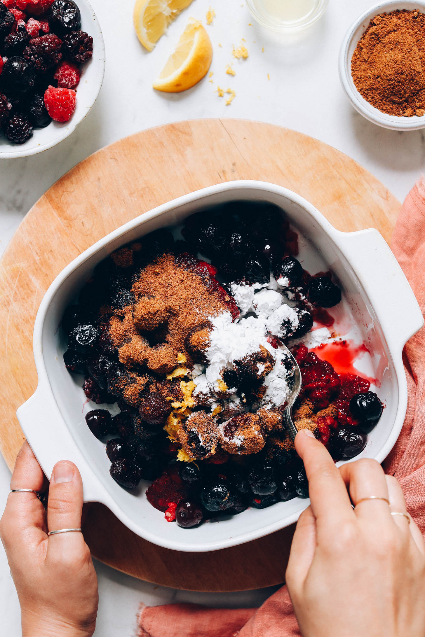 Stirring frozen berries, coconut sugar, arrowroot powder, and lemon zest