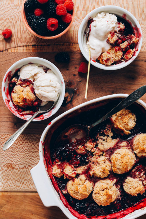 Pan and bowls of mixed berry cobbler with vanilla ice cream