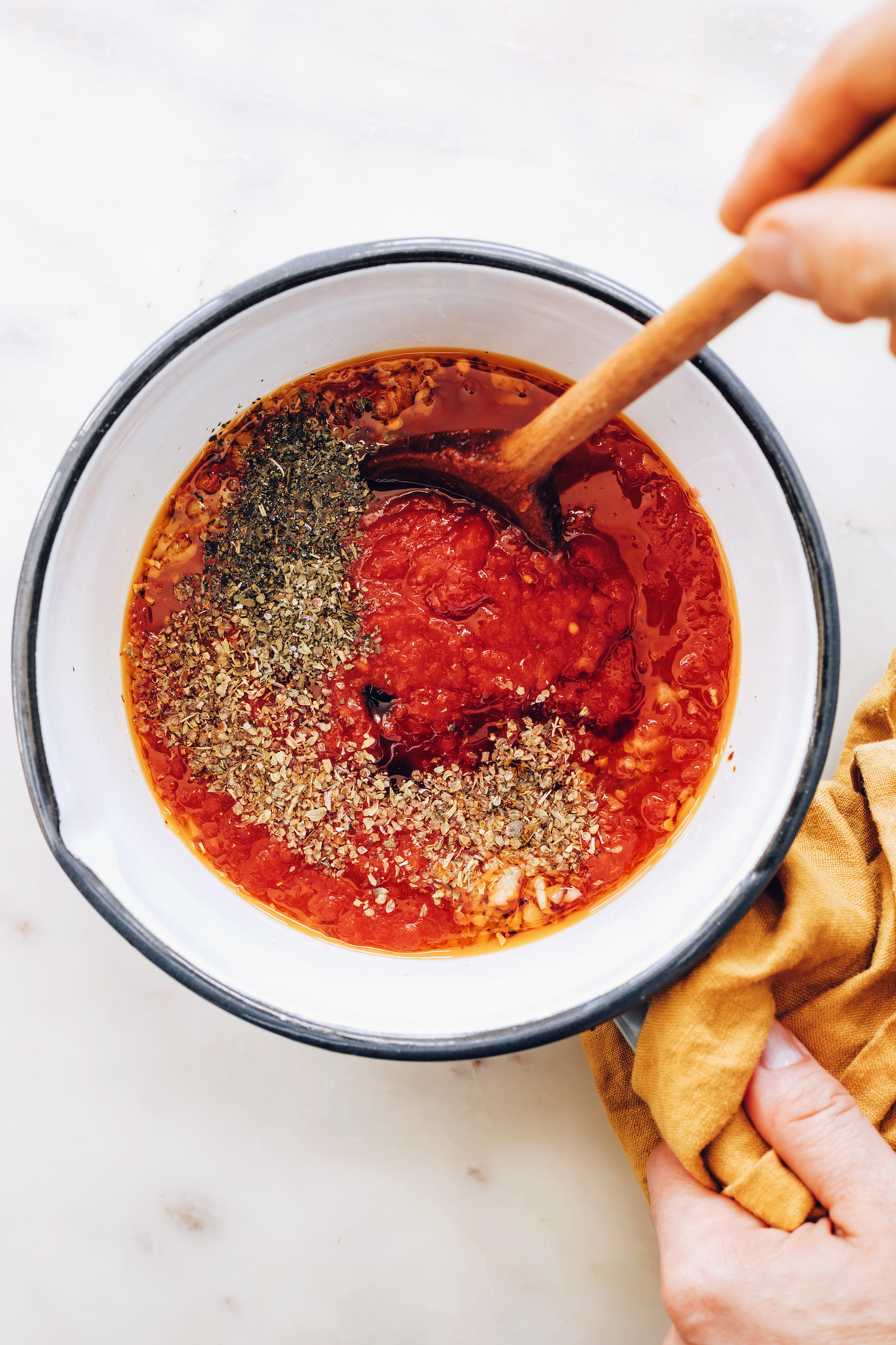Saucepan with crushed tomatoes, sautéed garlic and red pepper flakes, oregano, basil, salt, and maple syrup