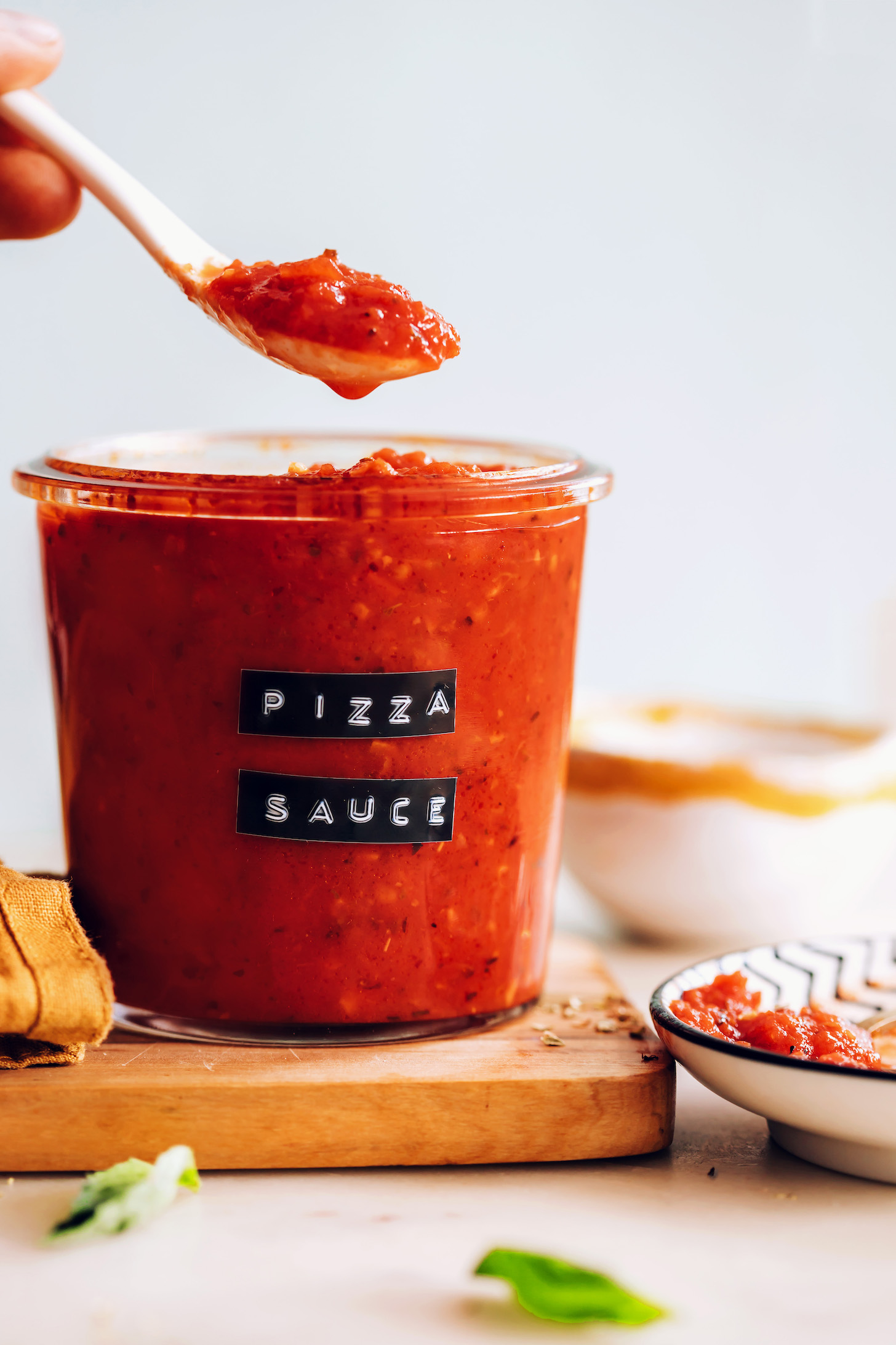 Spoon holding pizza sauce over a jar