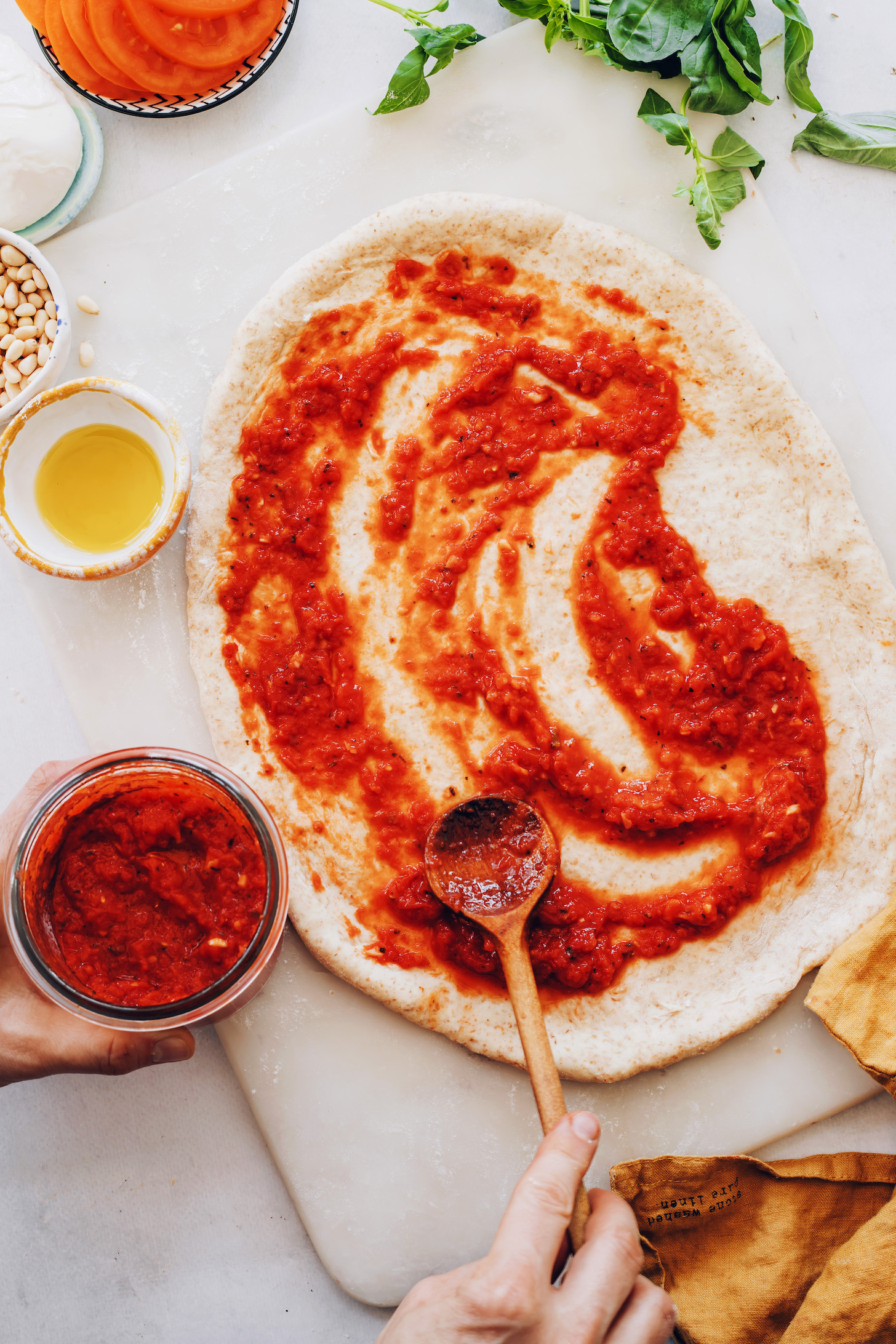 Spreading homemade pizza sauce onto pizza dough