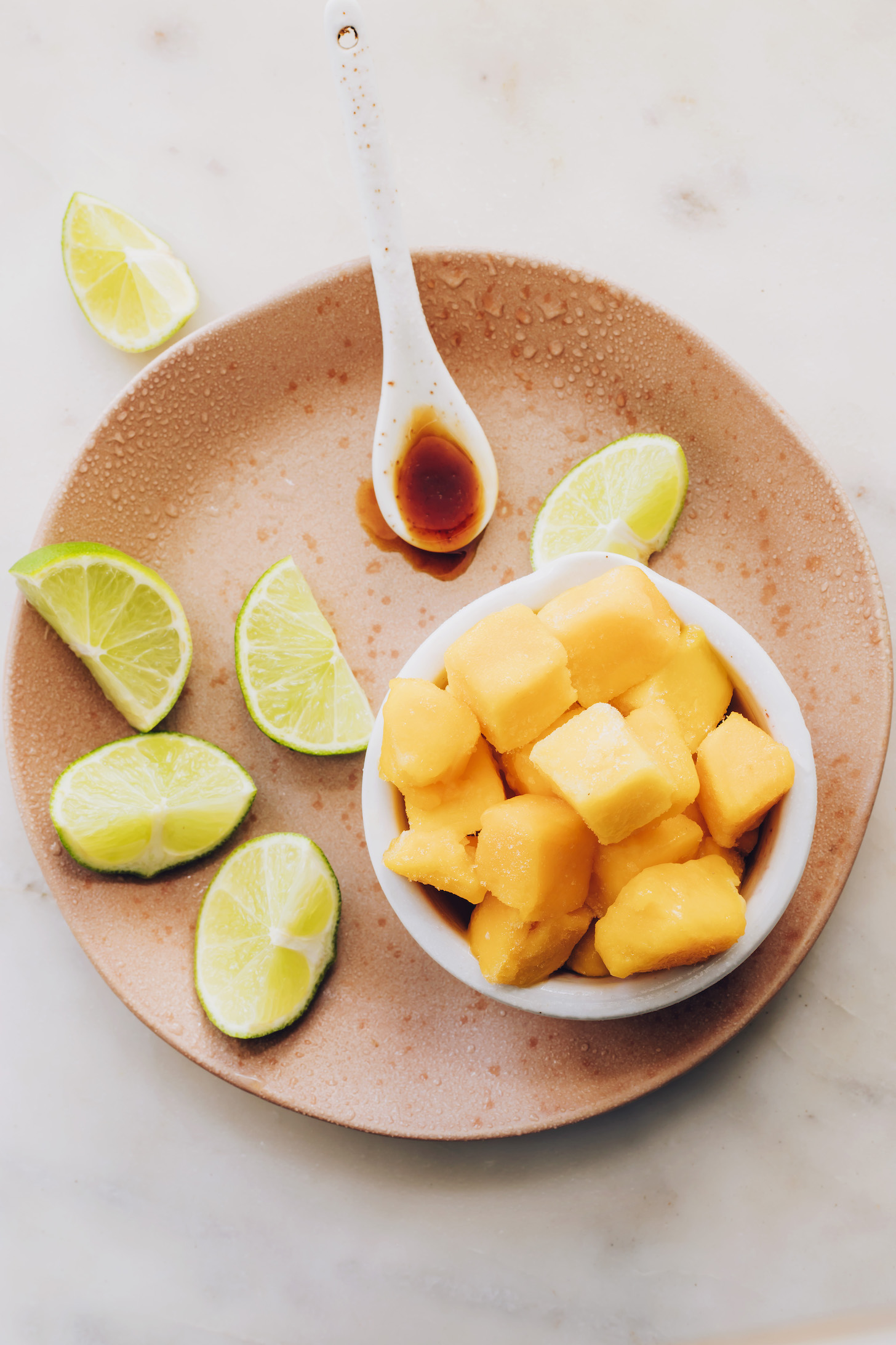 Lime wedges, frozen mango chunks, and a spoonful of maple syrup