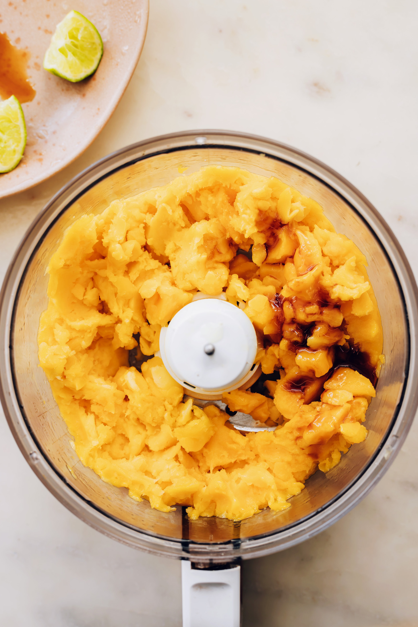 Maple syrup and lime juice in a food processor with frozen mango pieces