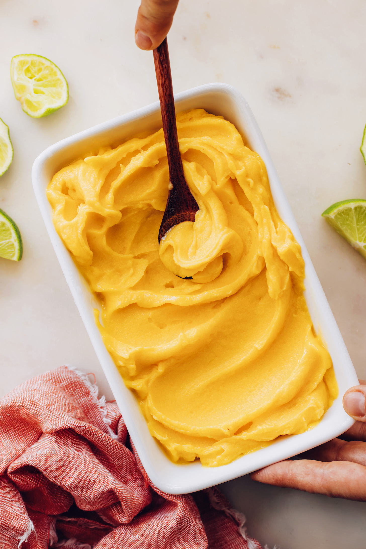 Wooden spoon in a pan of creamy mango sorbet made without an ice cream maker