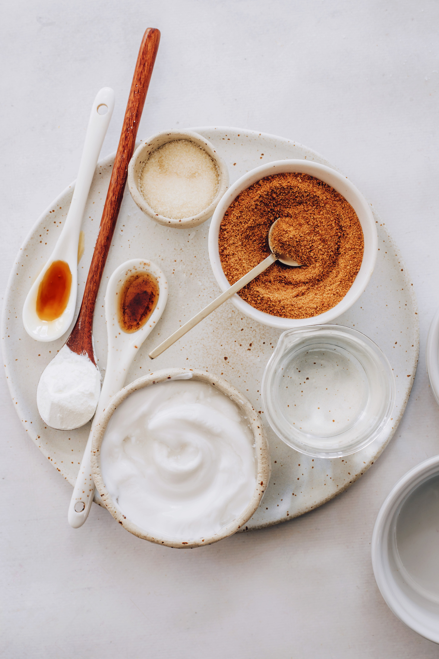 Bowls and spoons of coconut sugar, salt, vanilla, cornstarch, maple syrup, coconut milk, and water