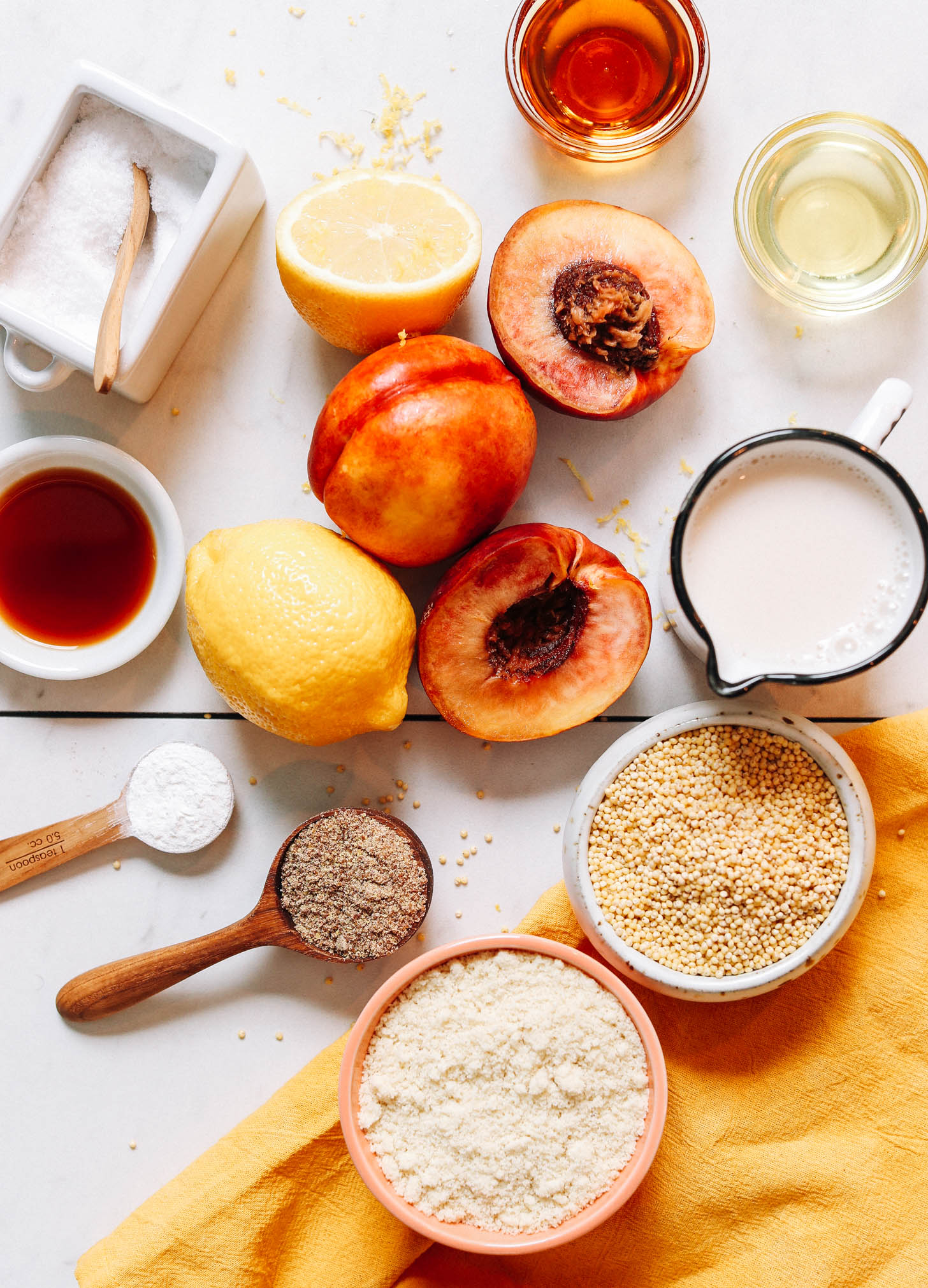 Salt, nectarines, lemon, maple syrup, vanilla, flaxseed, baking powder, almond flour, millet, almond milk, and avocado oil