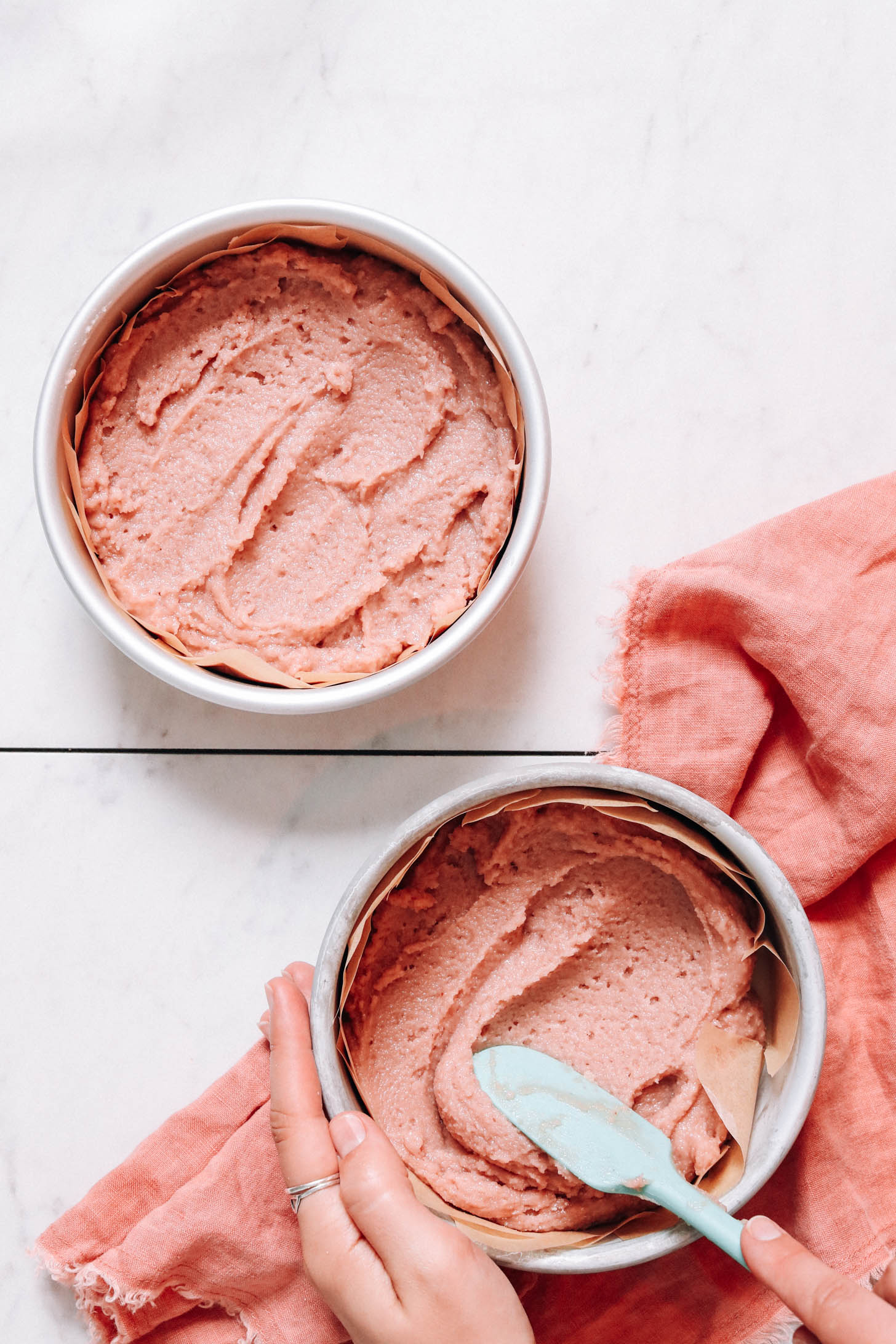 Two cake pans filled with strawberry cake batter