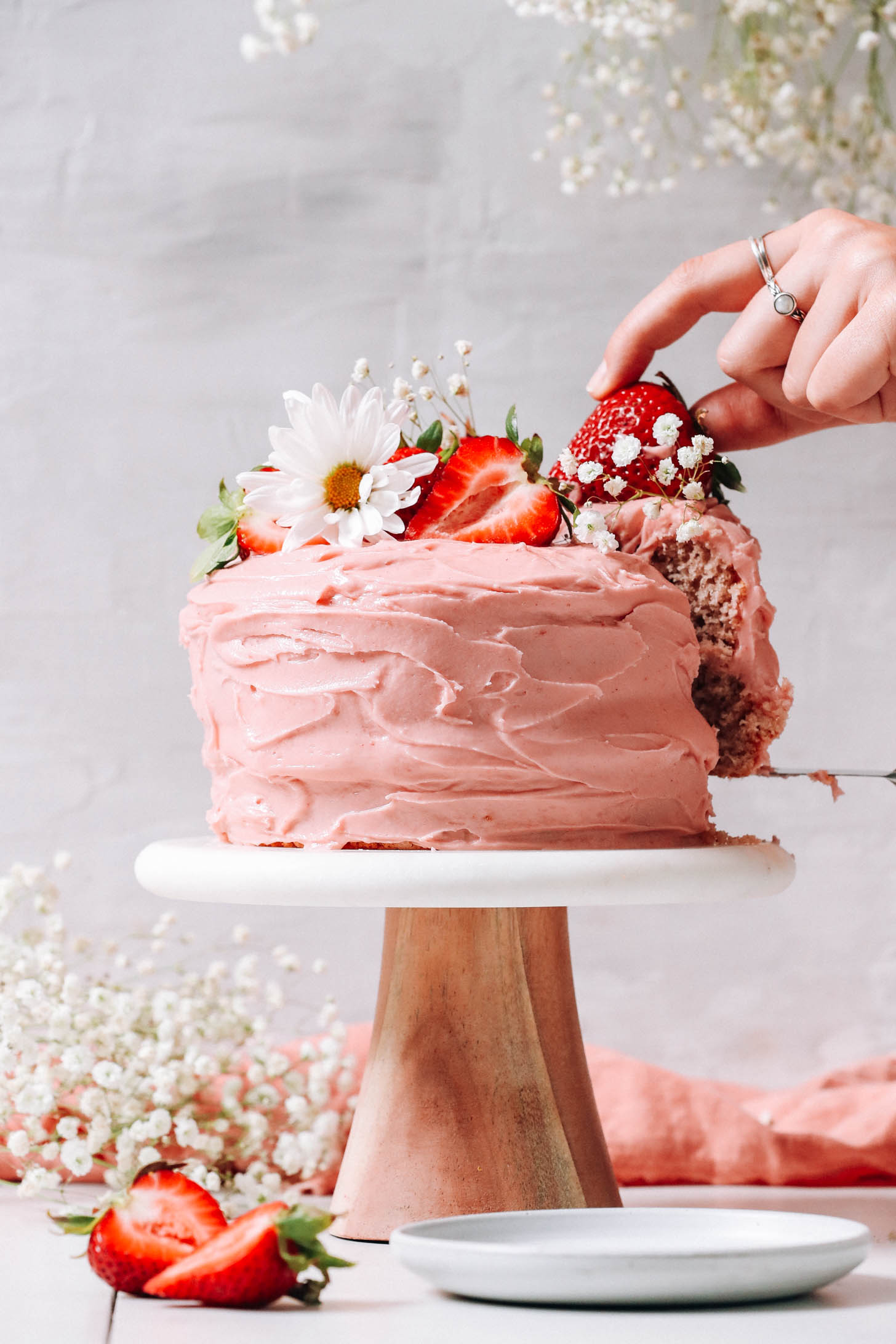 Gluten-free vegan strawberry cake decorated with fresh strawberries and flowers
