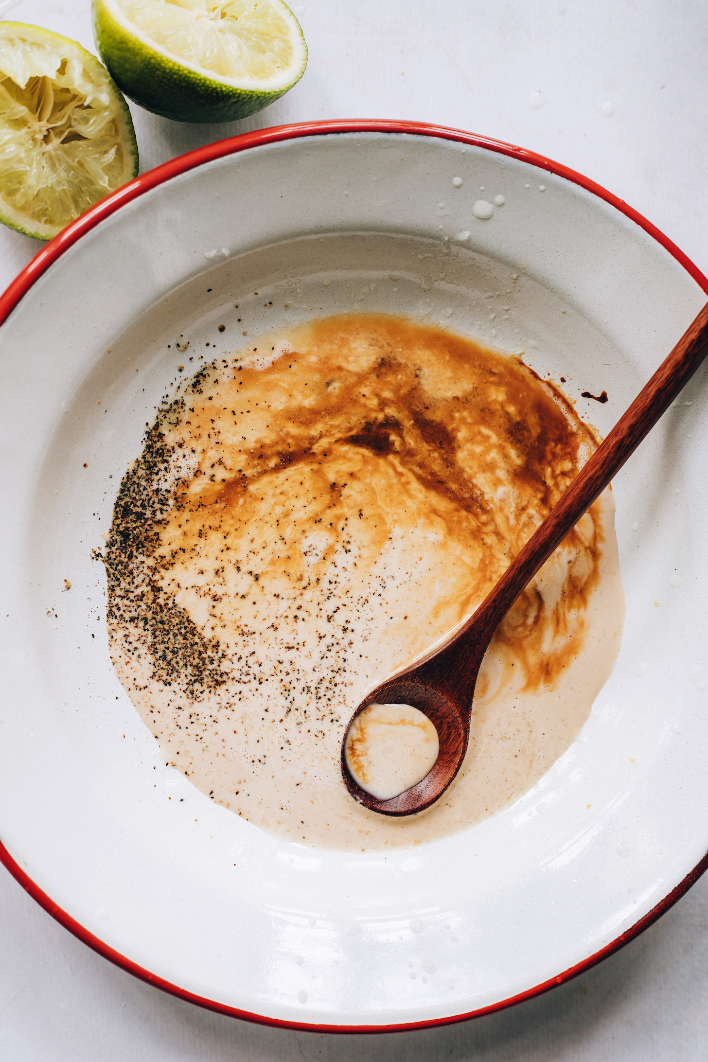 Bowl of tahini, lime juice, coconut aminos, salt, and pepper