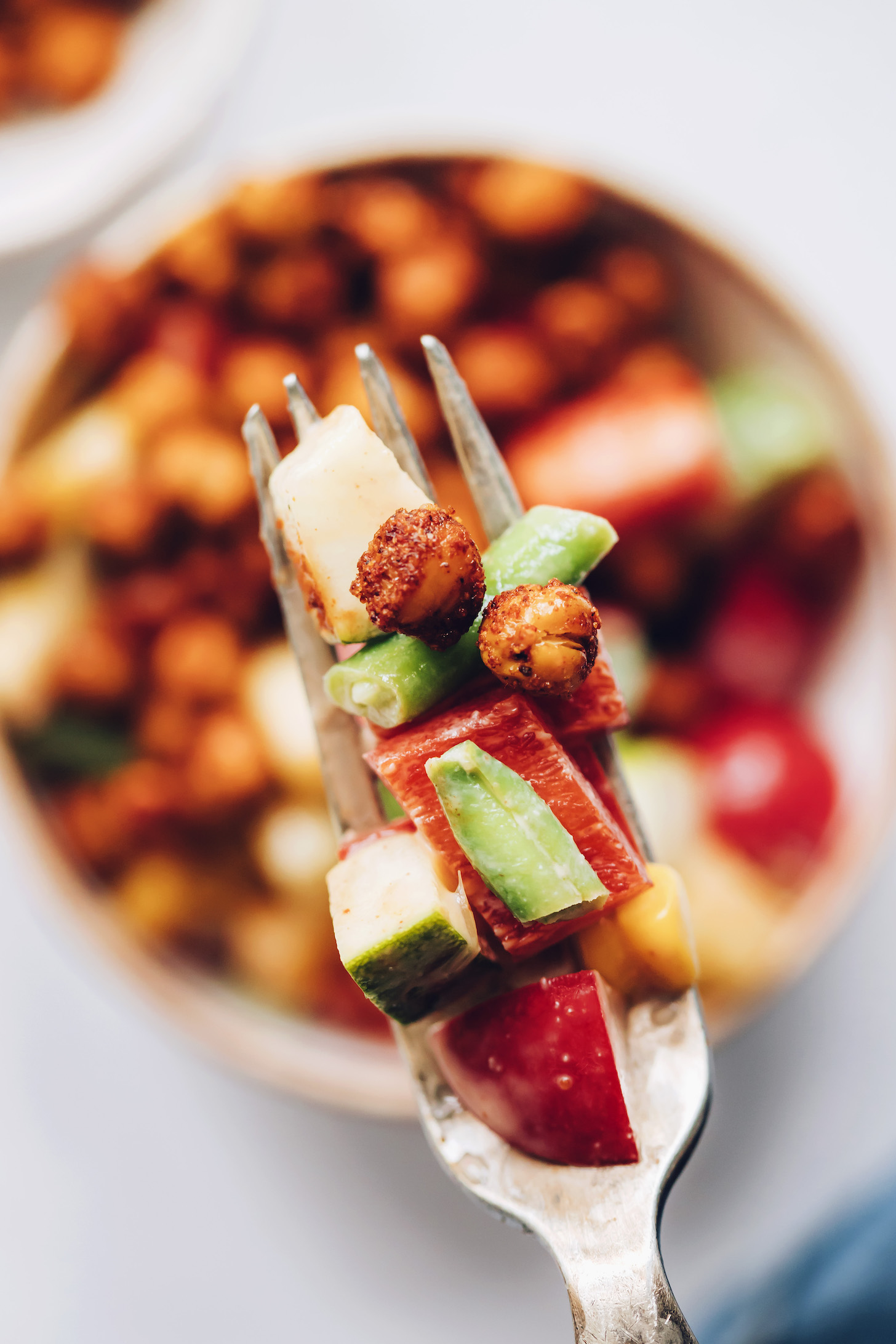 Fork with a bite of fresh chopped vegetables and chickpeas