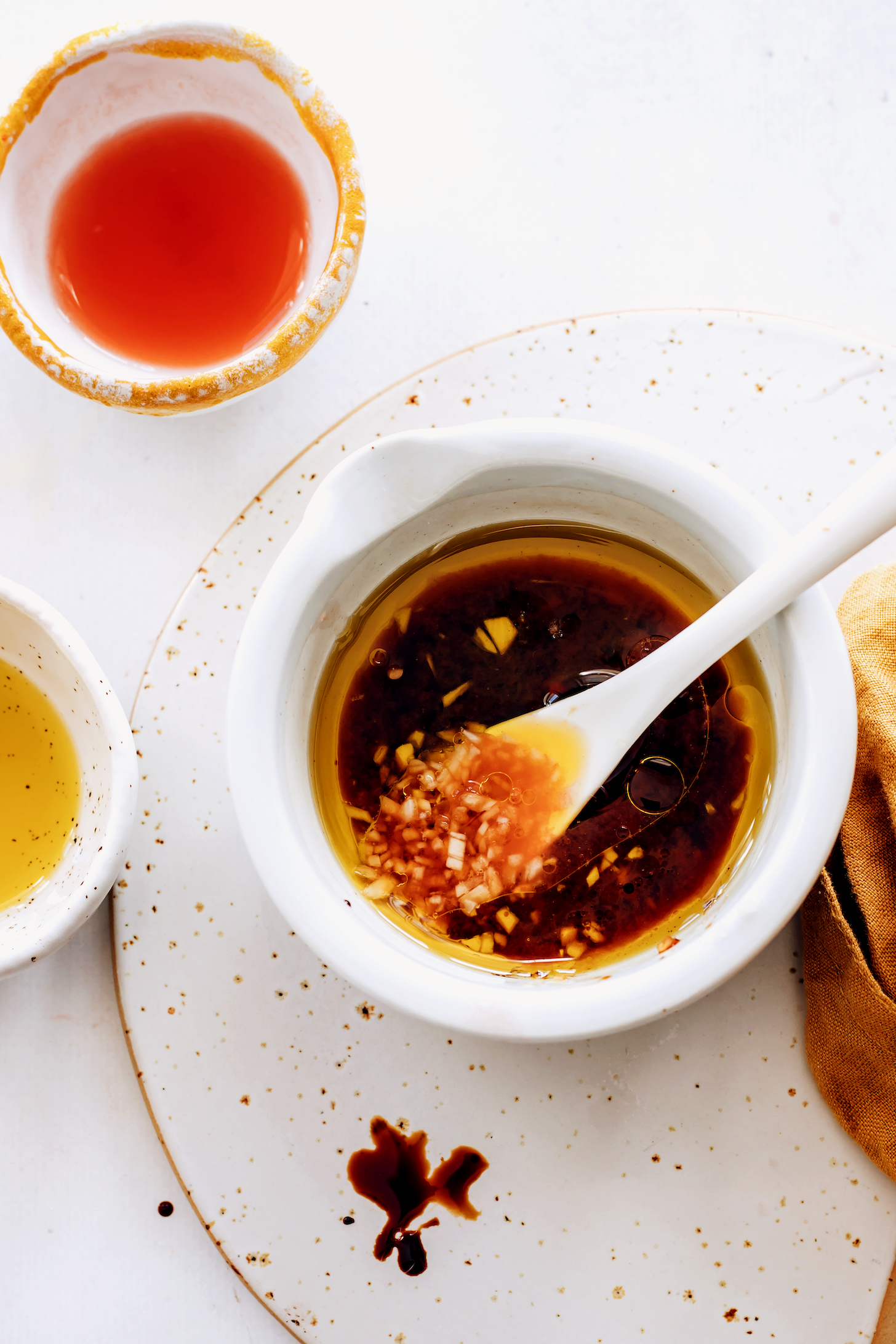 Bowl of dressing made with olive oil, balsamic vinegar, tomato juice, salt, and minced garlic