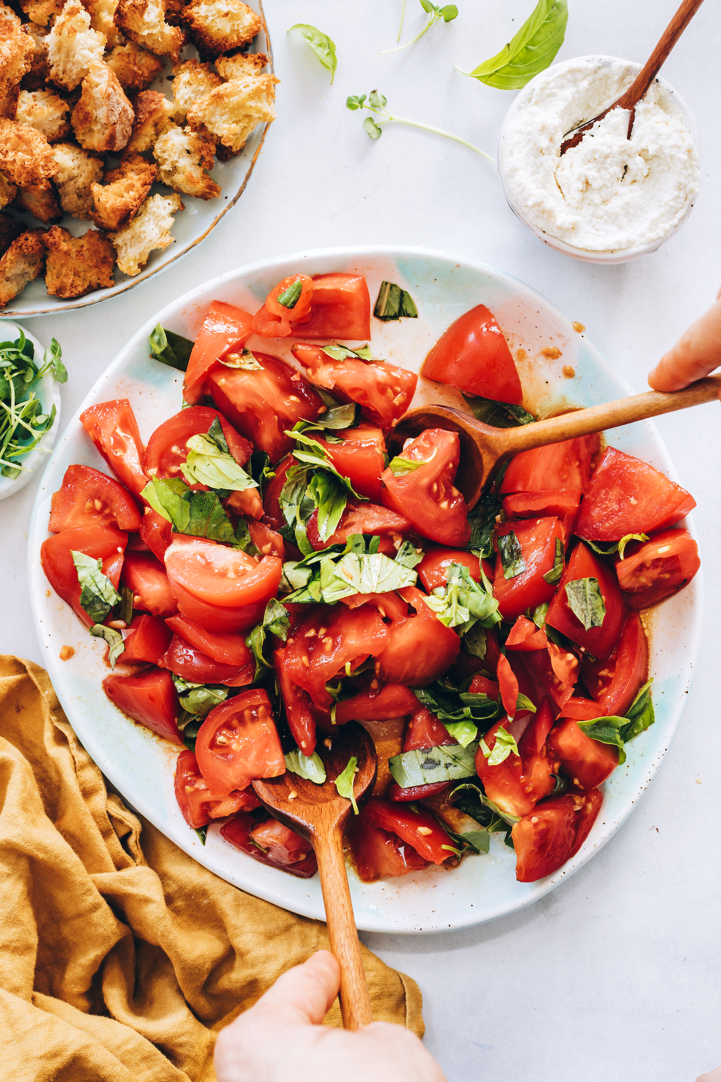 Tossing fresh tomatoes and basil with dressing