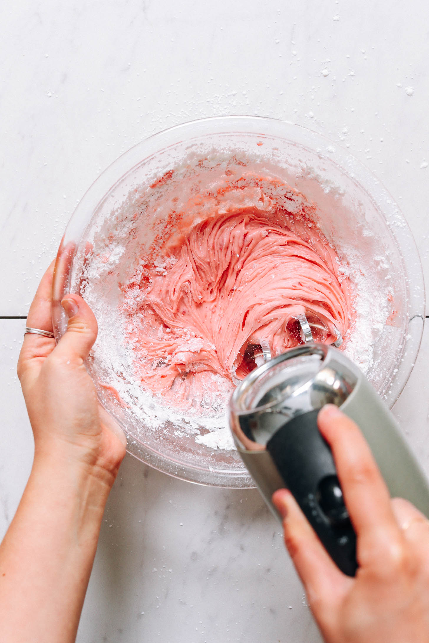 Whipping powdered sugar into the strawberry purée and vegan butter