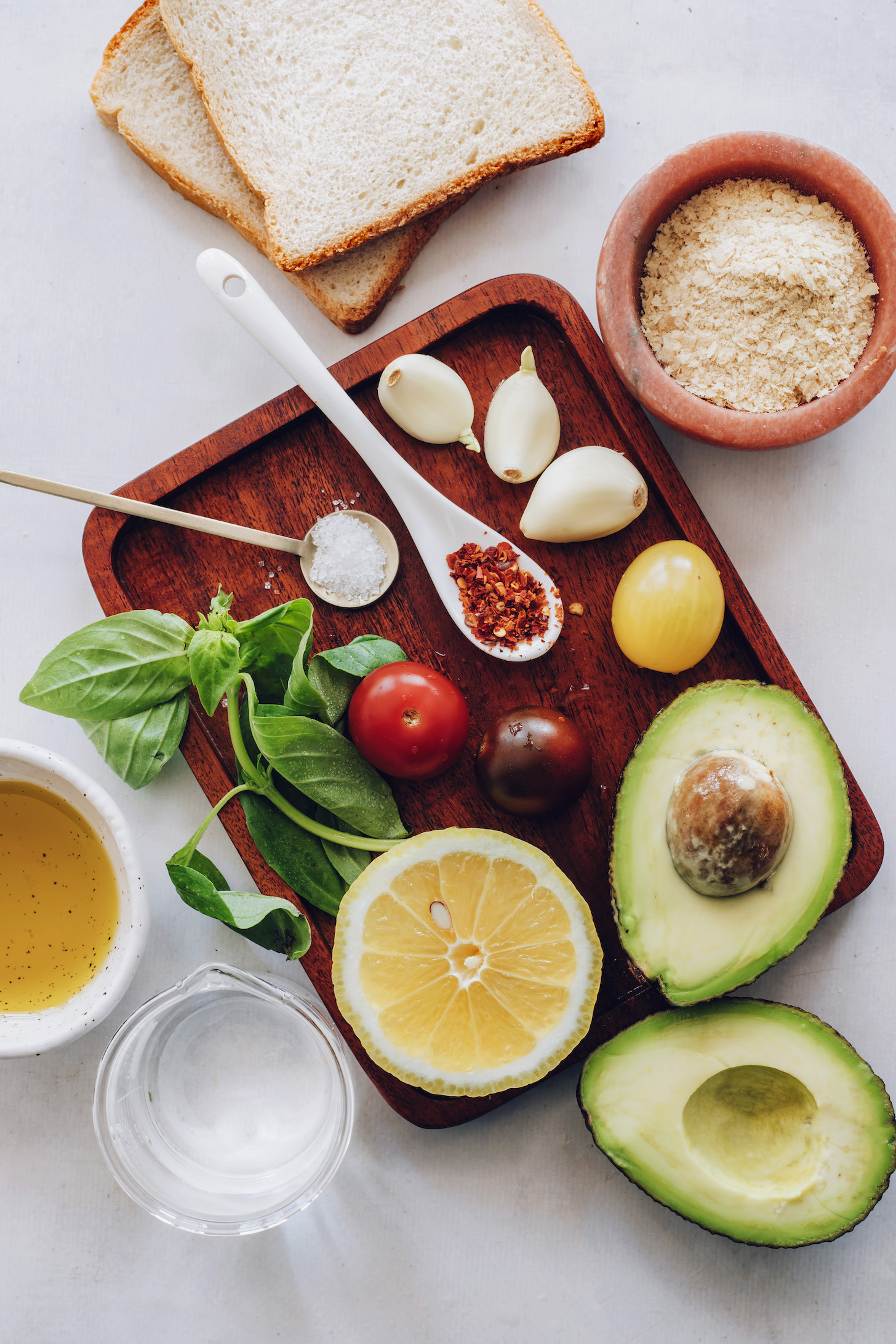 Bread, nutritional yeast, garlic, cherry tomatoes, avocado, salt, red pepper flakes, basil, lemon, water, and olive oil