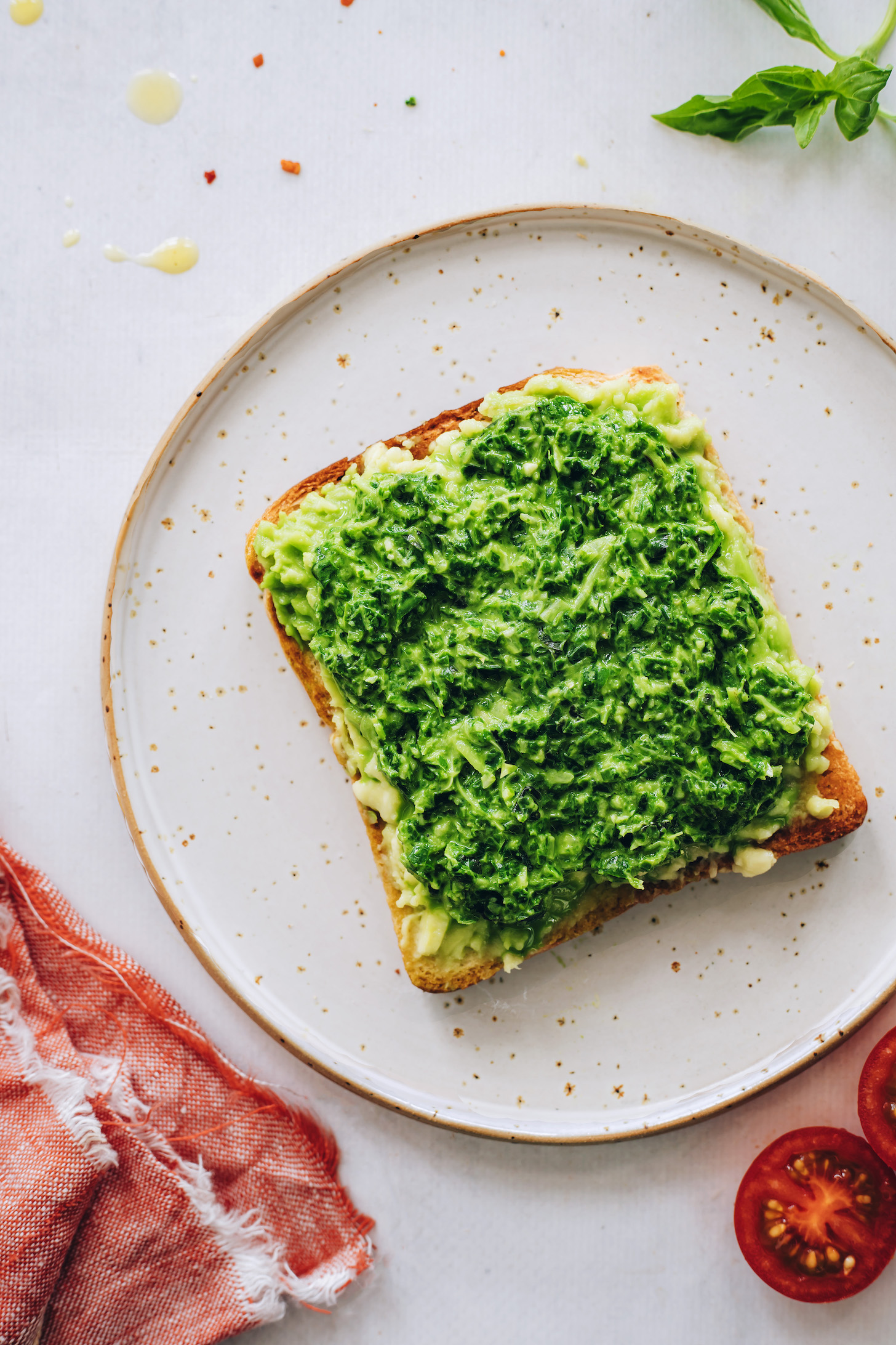 Slice of toast topped with mashed avocado and basil pesto