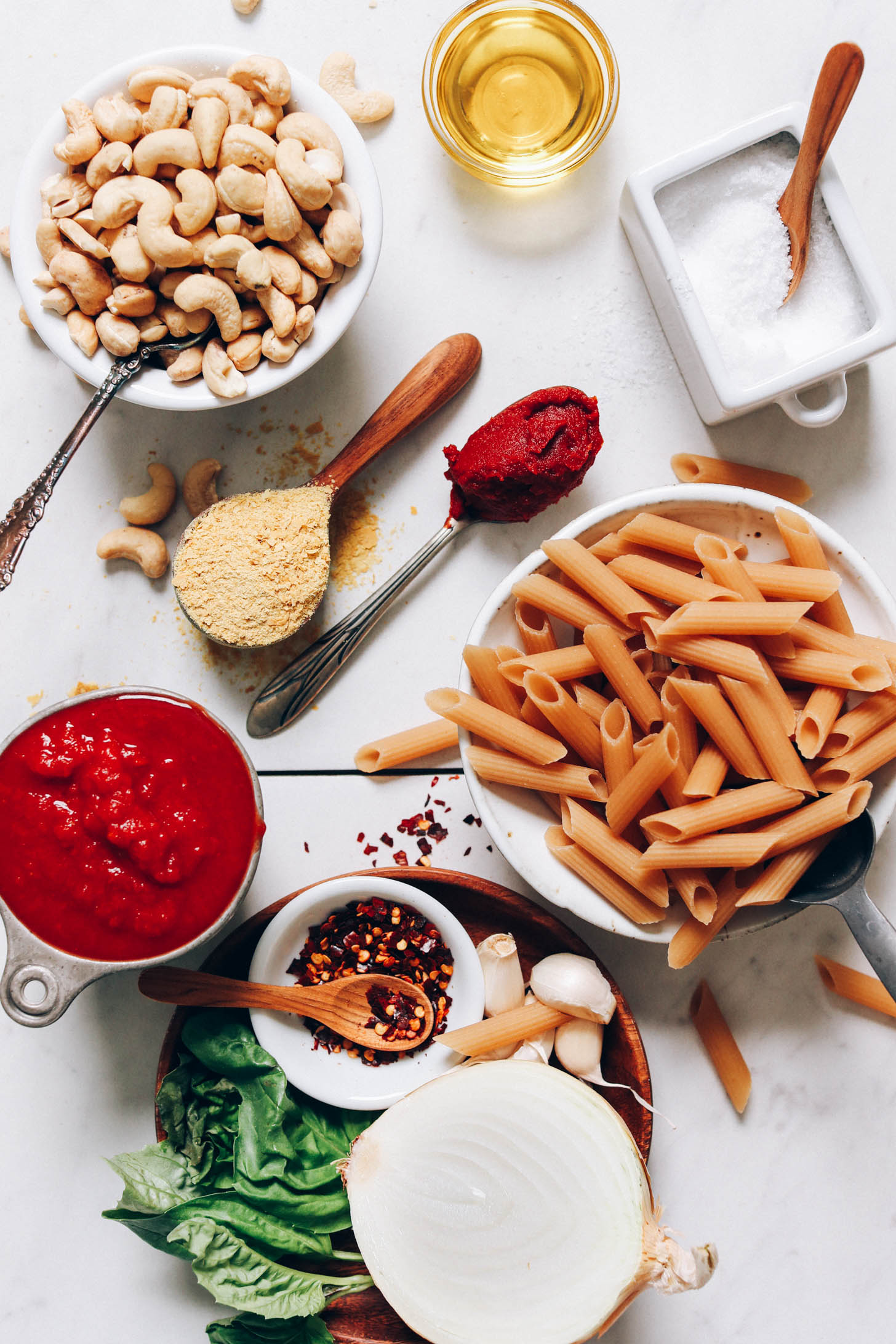 Cashews, nutritional yeast, tomato paste, olive oil, salt, penne noodles, garlic, onion, basil, and crushed tomatoes