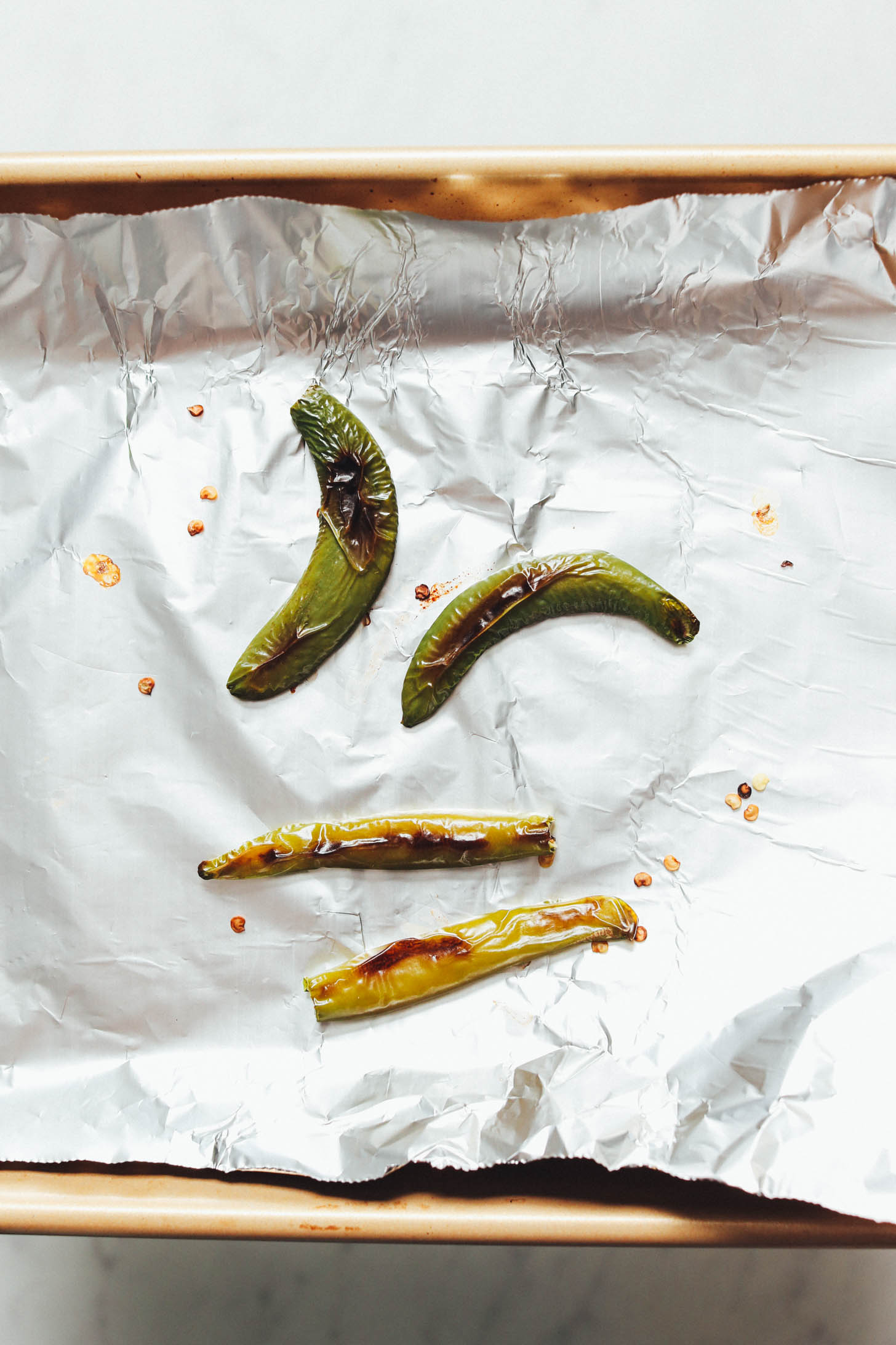 Roasted serrano peppers on a foil-lined baking sheet