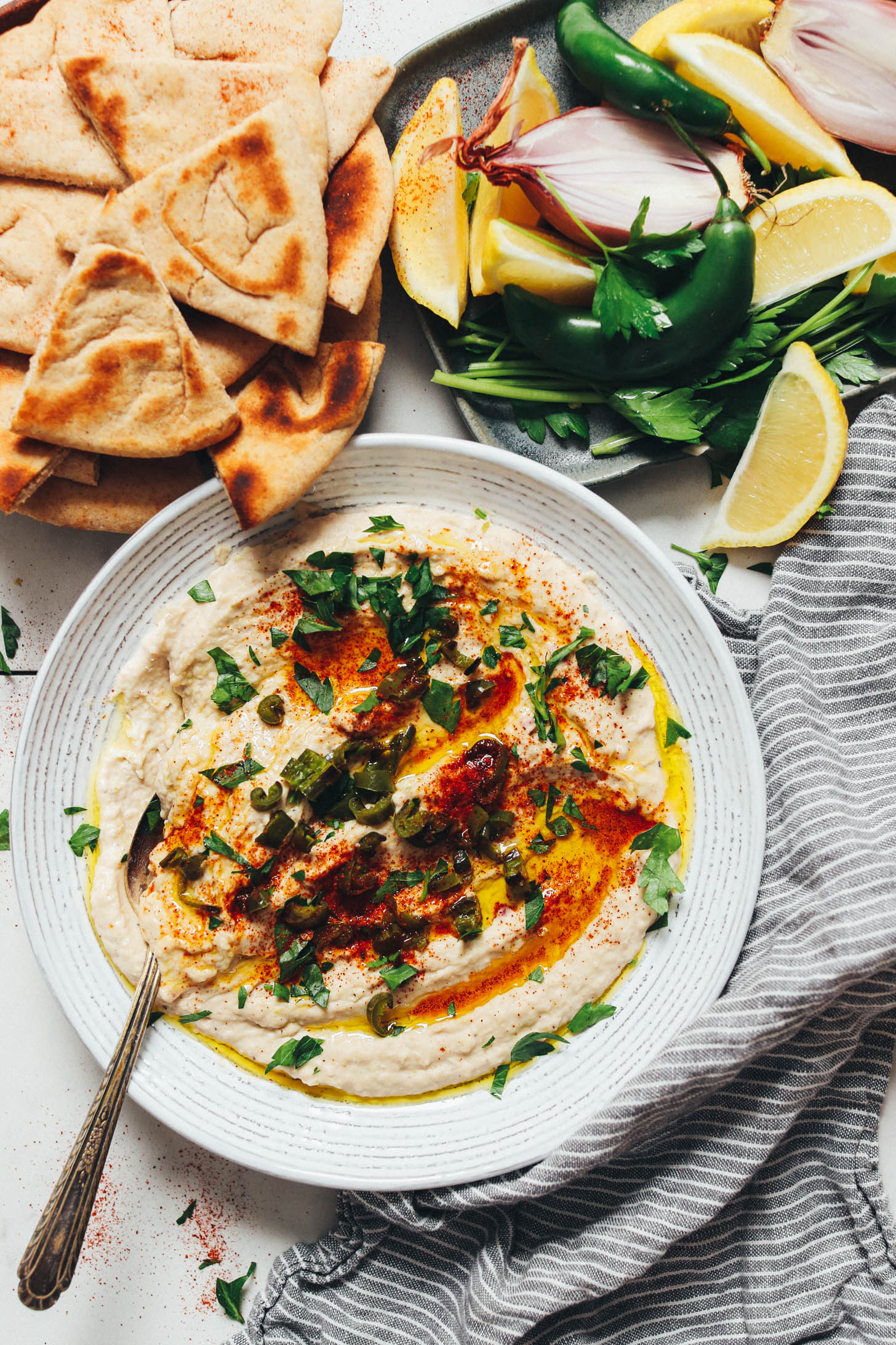 Serranos, lemon slices, shallot, parsley, and pita bread next to a bowl of homemade white bean dip