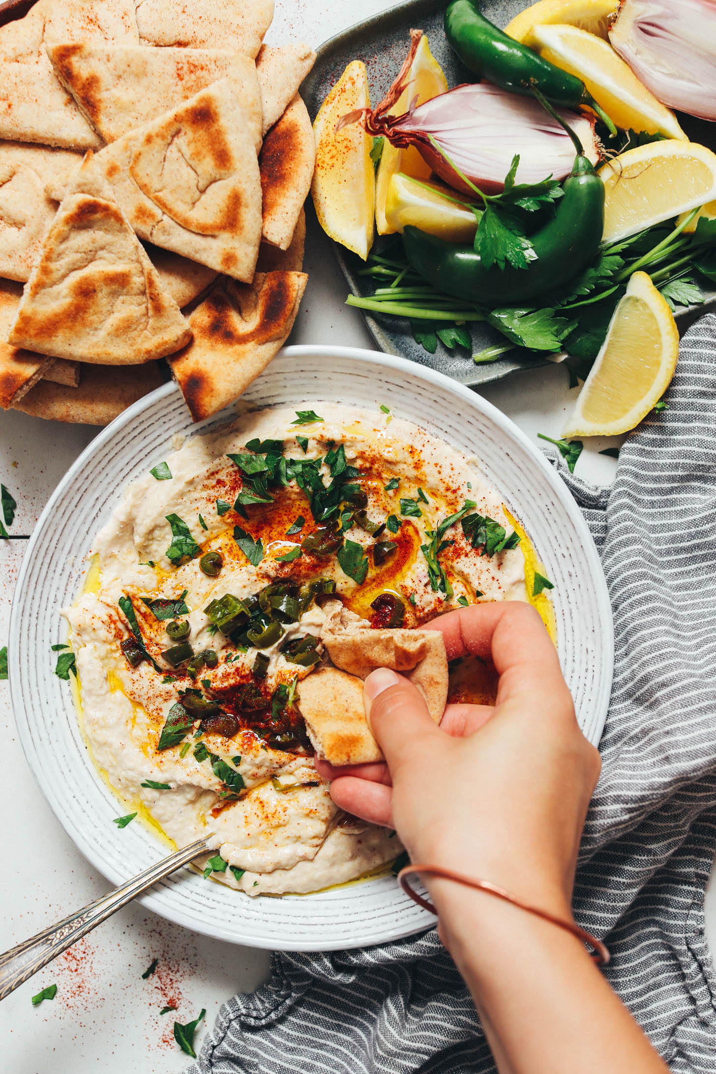Scooping up white bean dip with a slice of pita bread