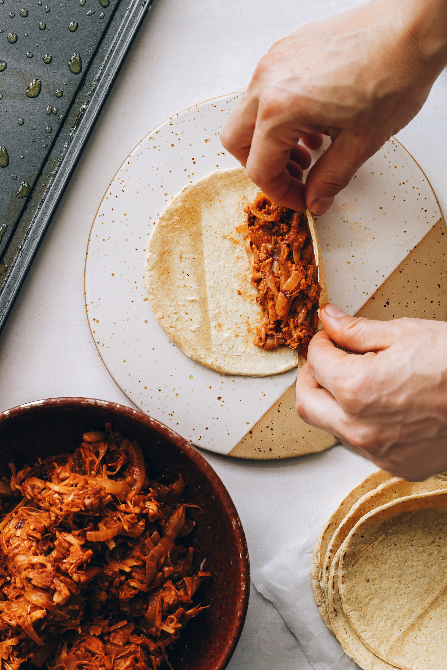 Rolling jackfruit filling in a corn tortilla