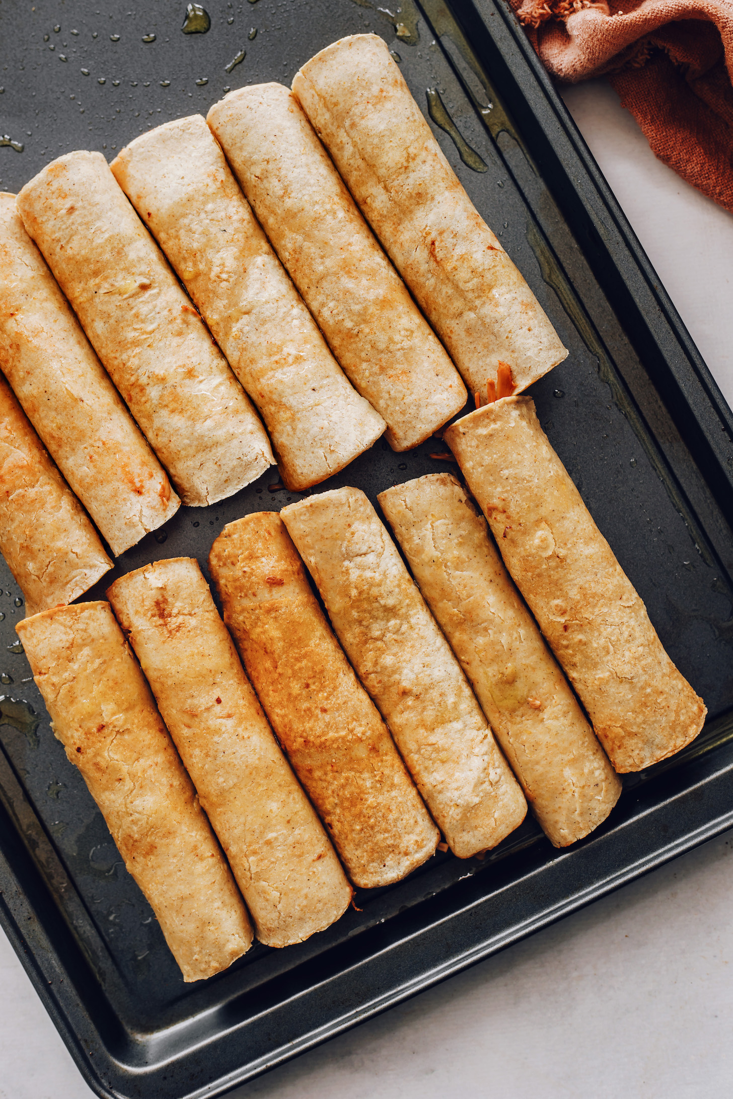 Vegan taquitos on a baking sheet ready to go in the oven
