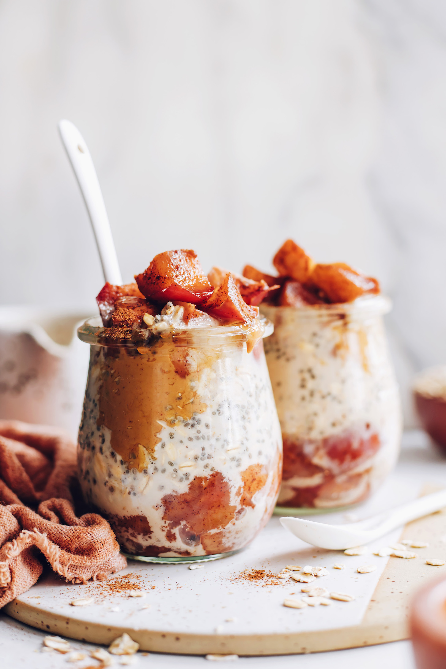 Side view of two jars of overnight oats topped with cooked apples