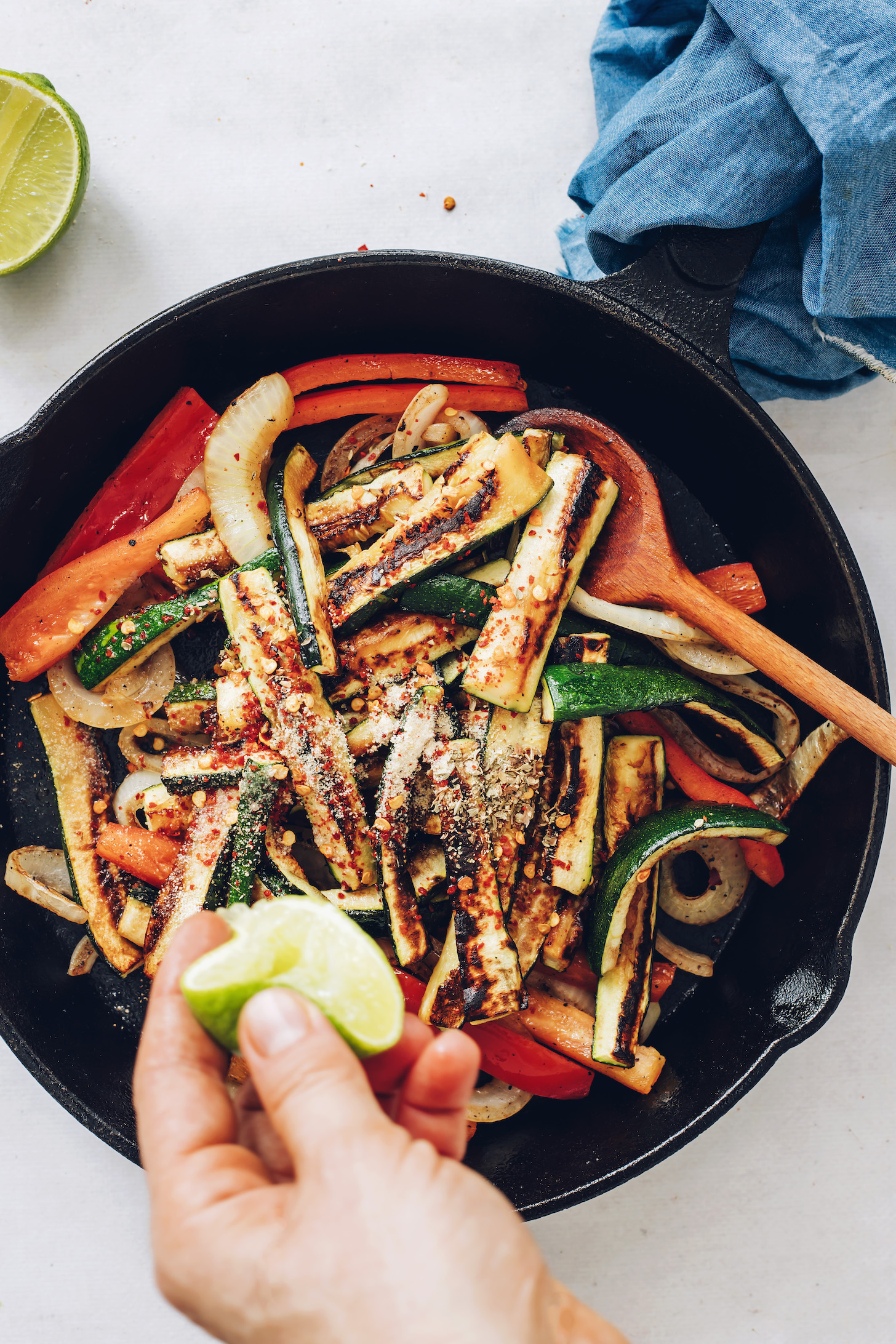 Squeezing lime into a skillet of sautéed onion, zucchini, bell pepper, and spices
