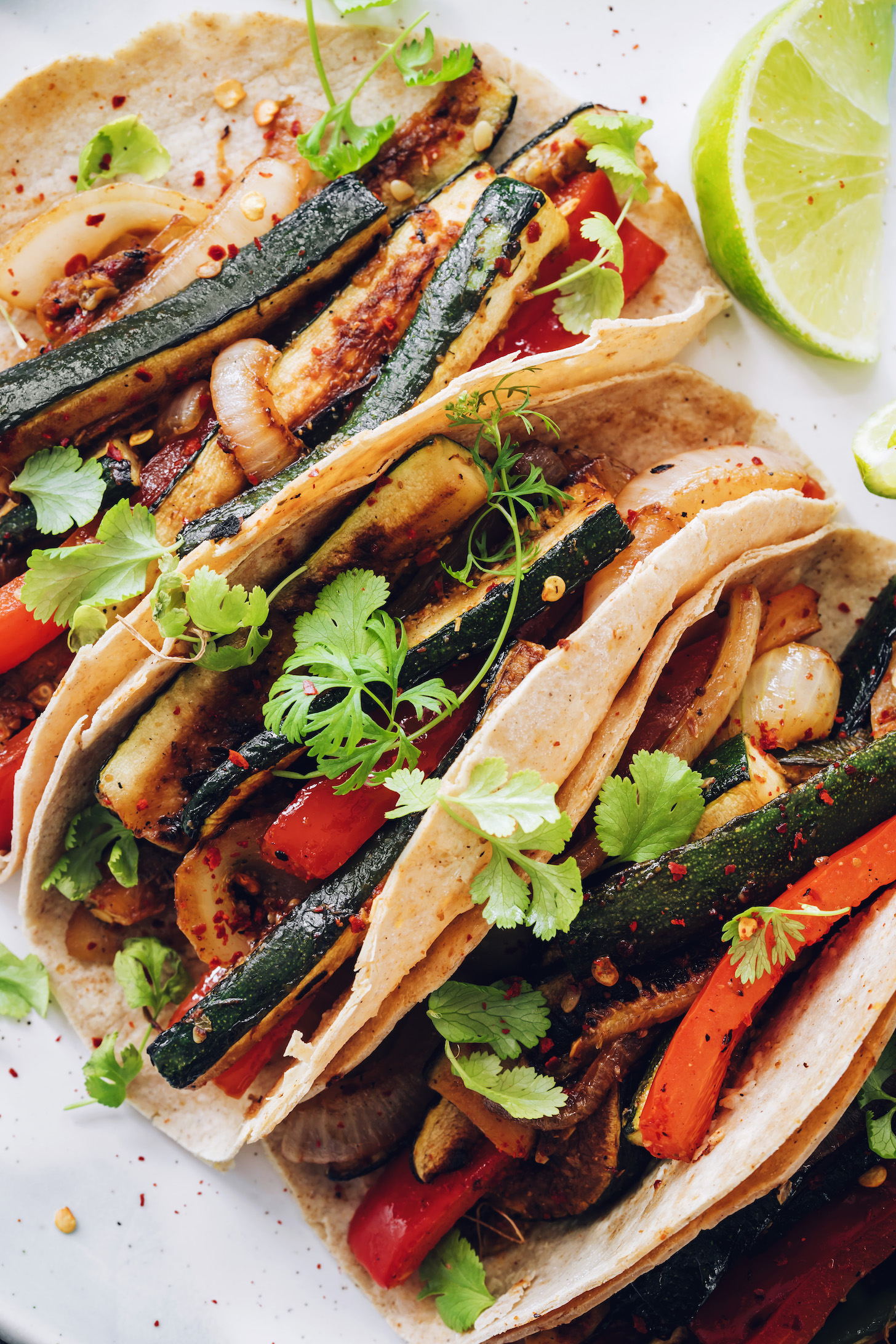 Close up shot of three vegan tacos made with zucchini, bell pepper, and onion