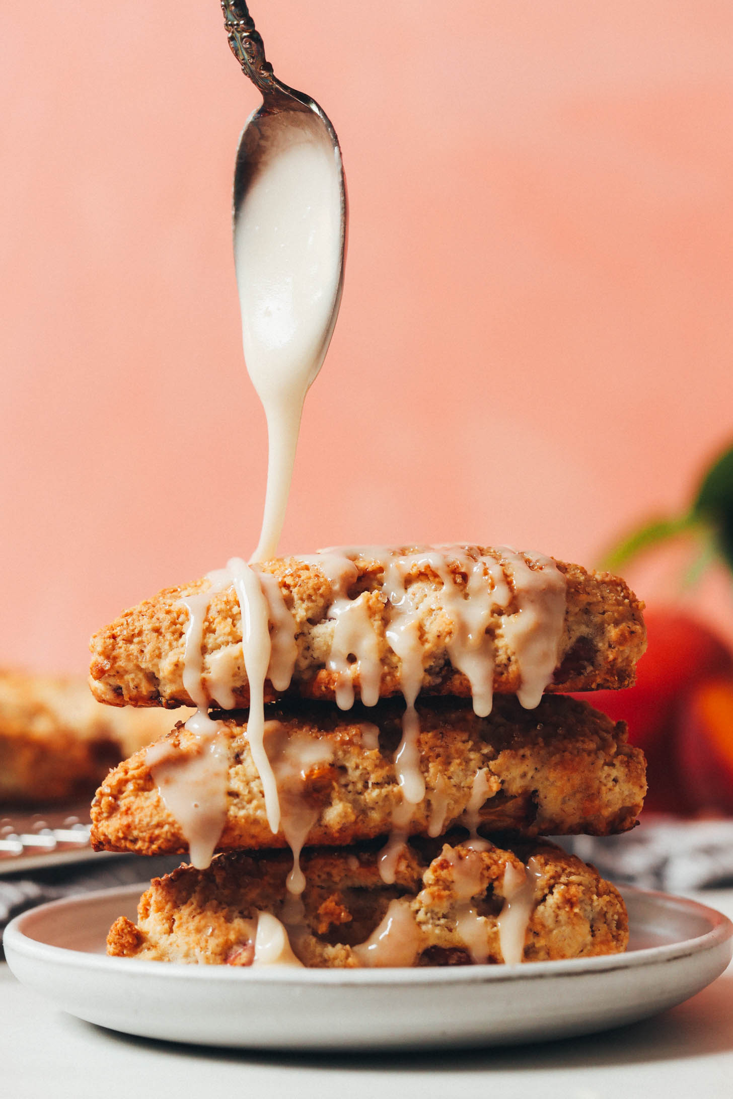 Drizzling a vanilla powdered sugar glaze over a stack of gluten-free vegan scones
