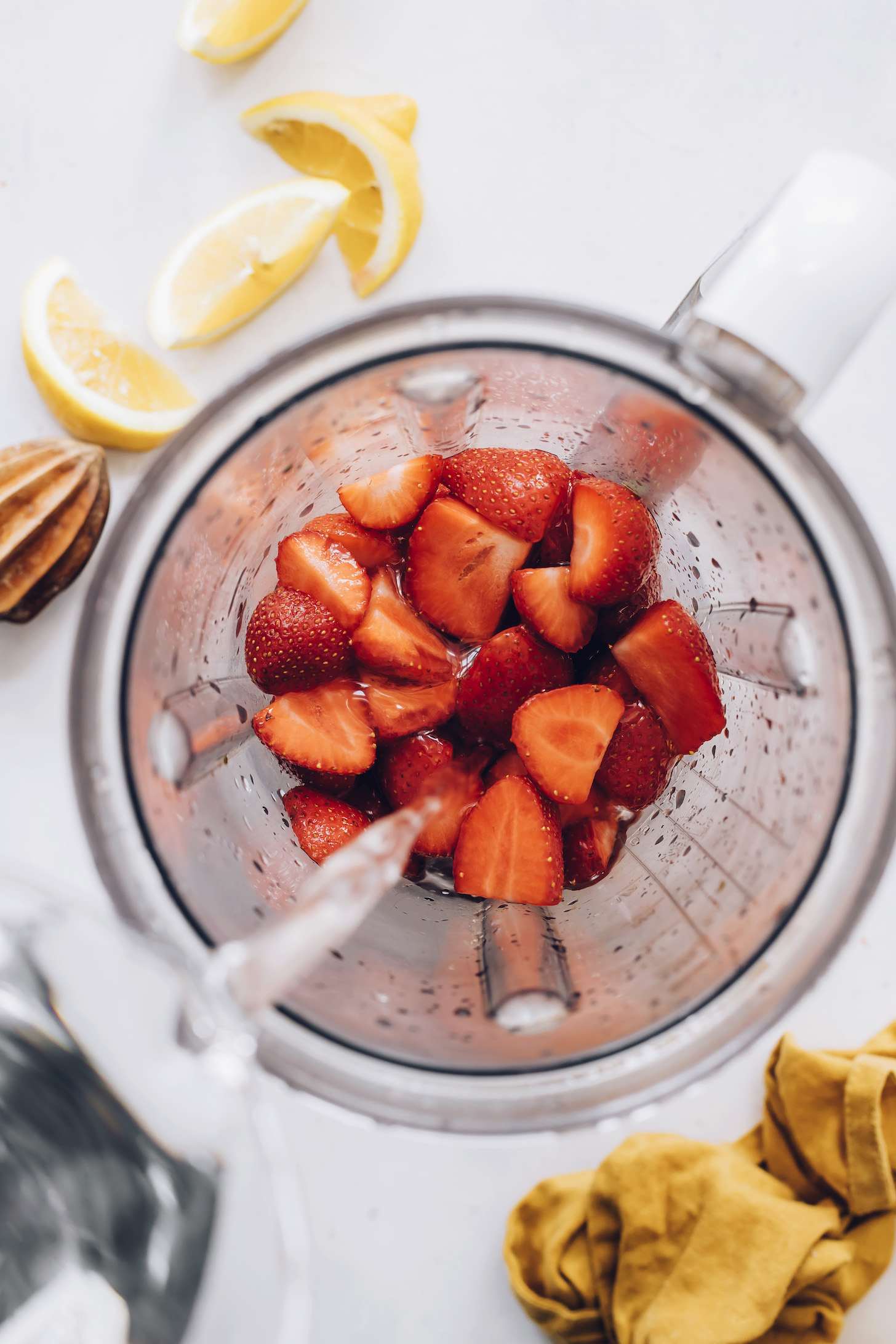 Pouring water over strawberries in a blender