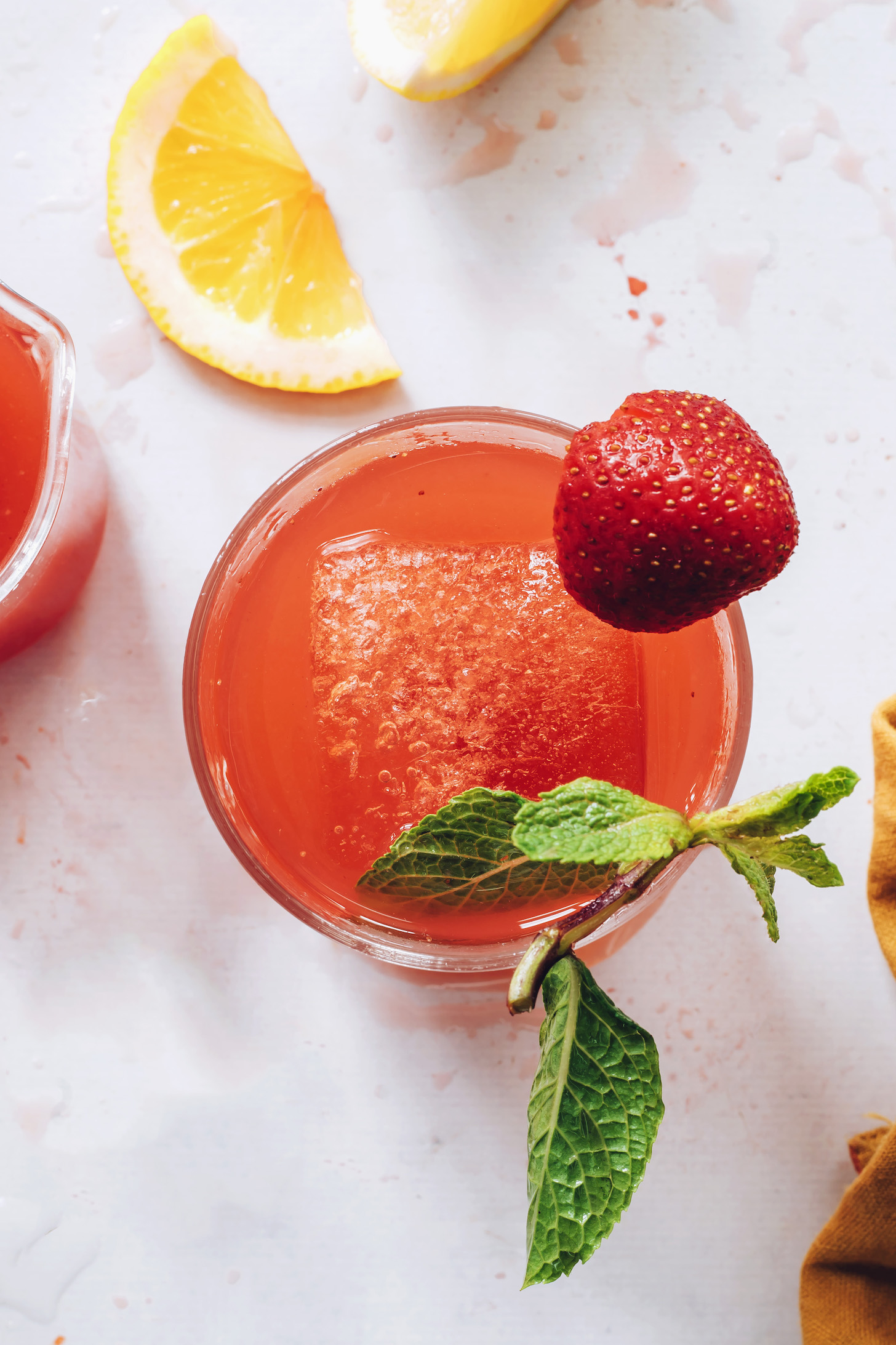 Top down shot of a glass of strawberry lemonade with a strawberry on the rim