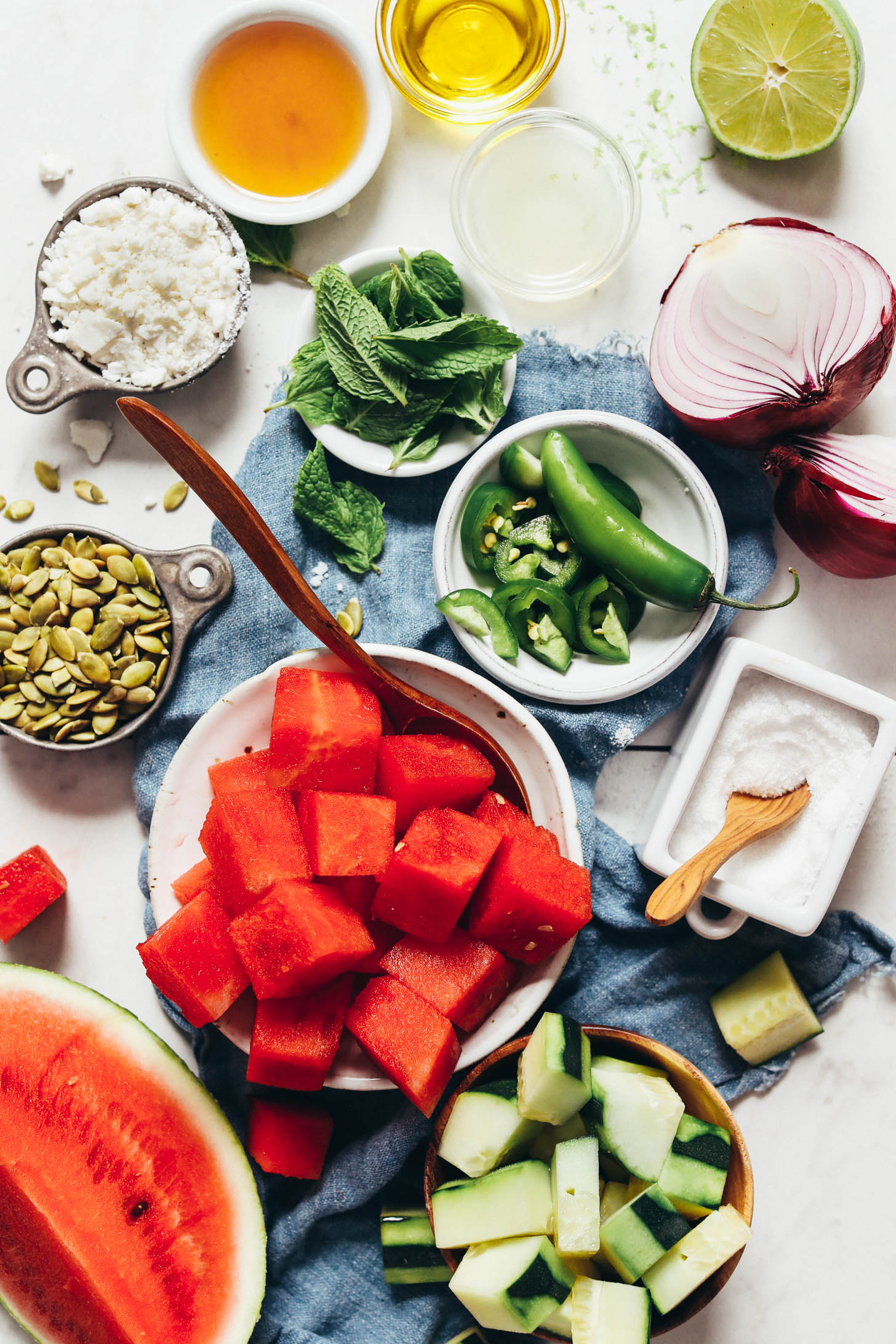 Watermelon, cucumber, salt, jalapeño, red onion, lime, olive oil, mint, maple syrup, vegan feta, and pumpkin seeds