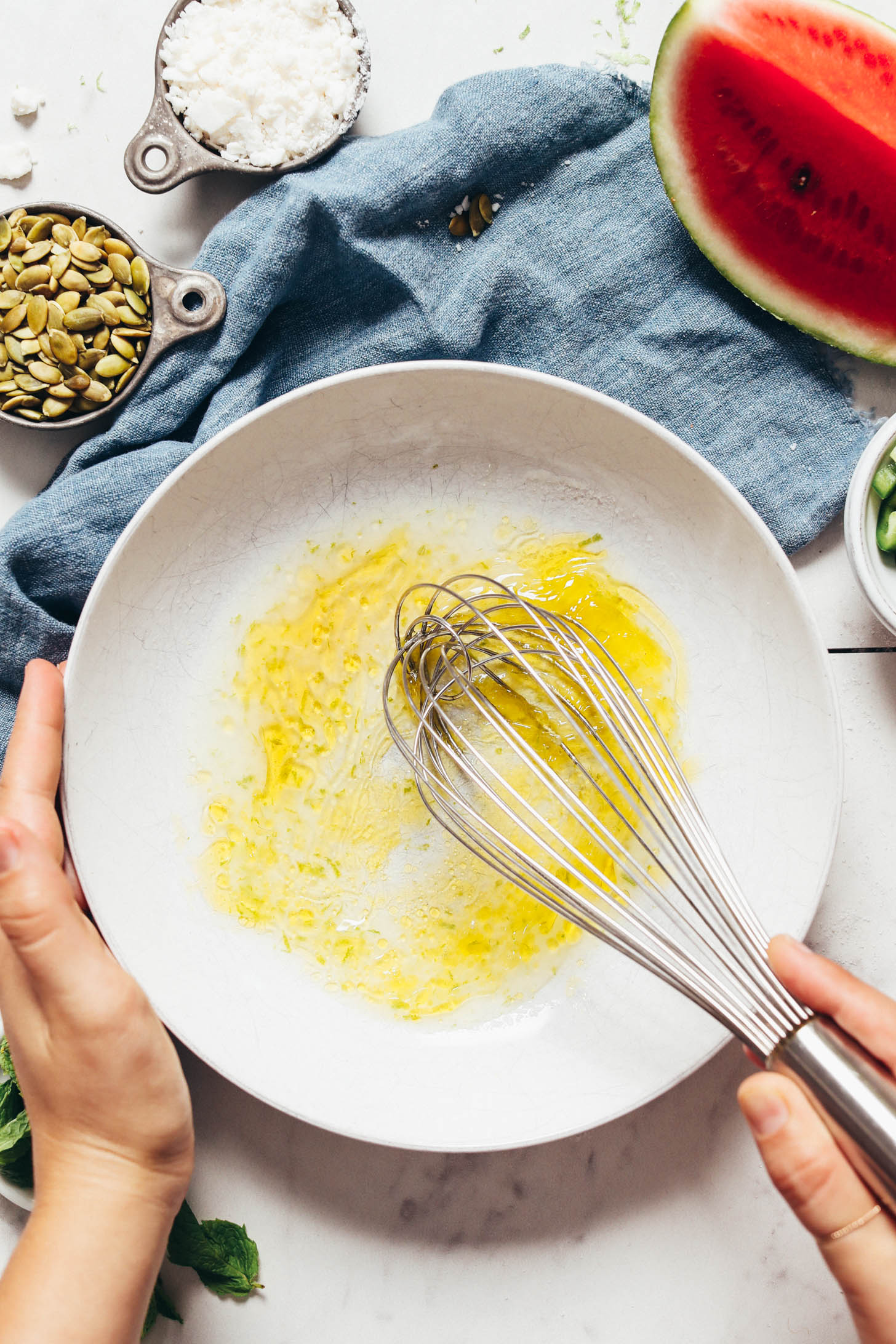 Whisking lime juice, zest, olive oil, salt, and maple syrup in a bowl