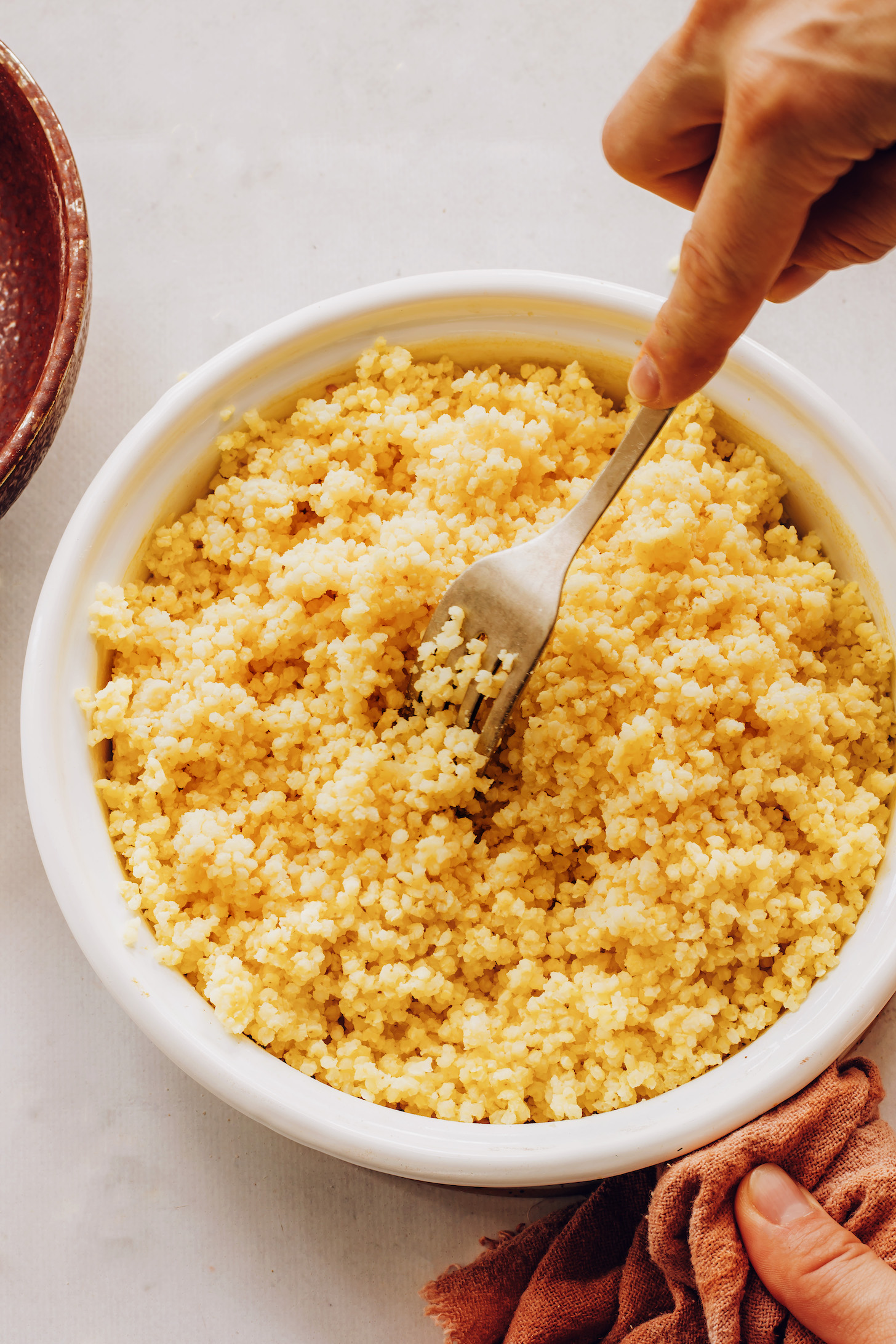 Using a fork to a fluff a pot of millet