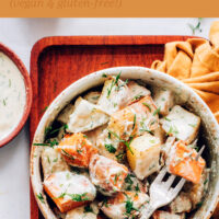 Bowl of easy vegan roasted potato salad with garlic dill dressing with a fork in it