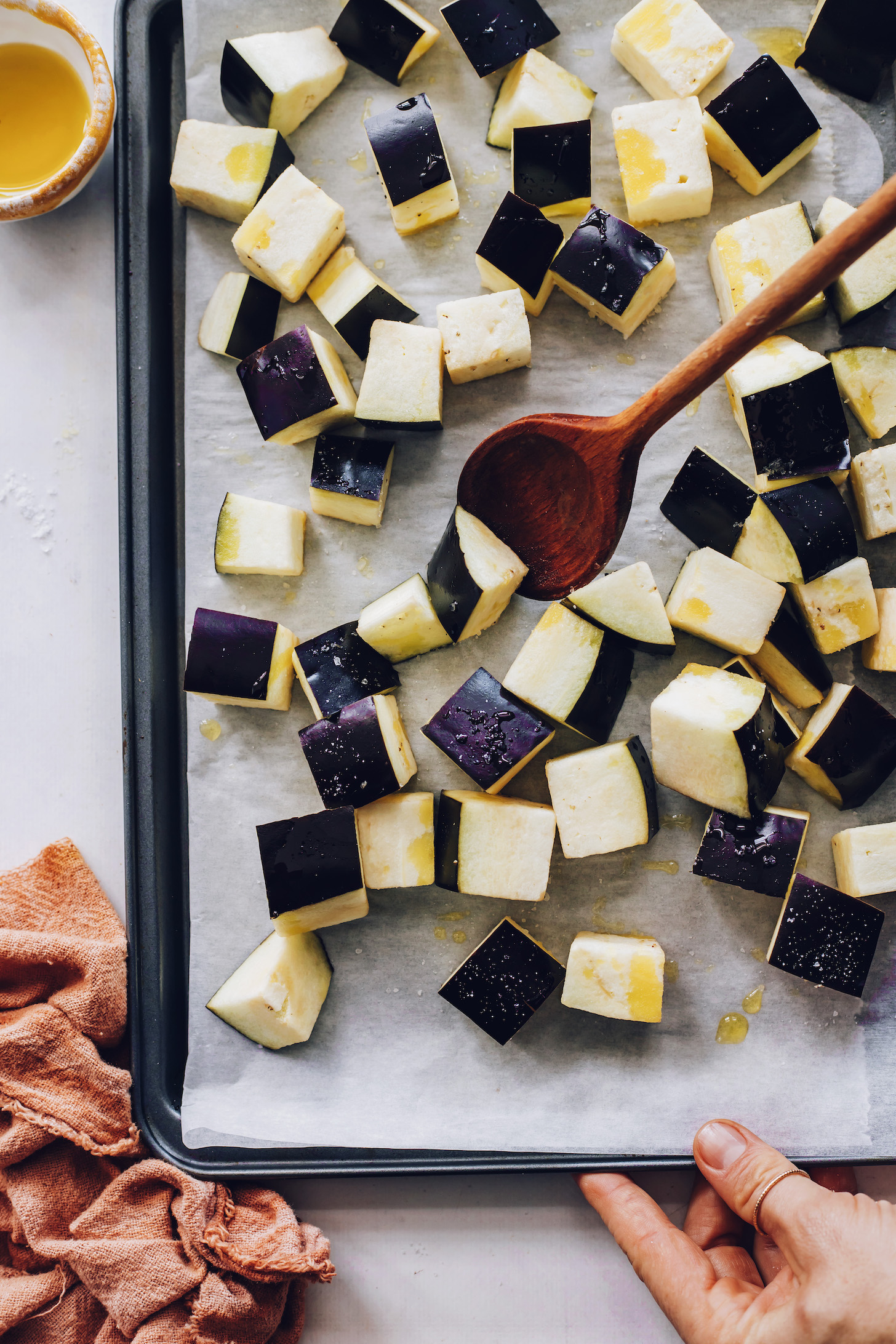Baking sheet of cubed eggplant topped with olive oil and salt