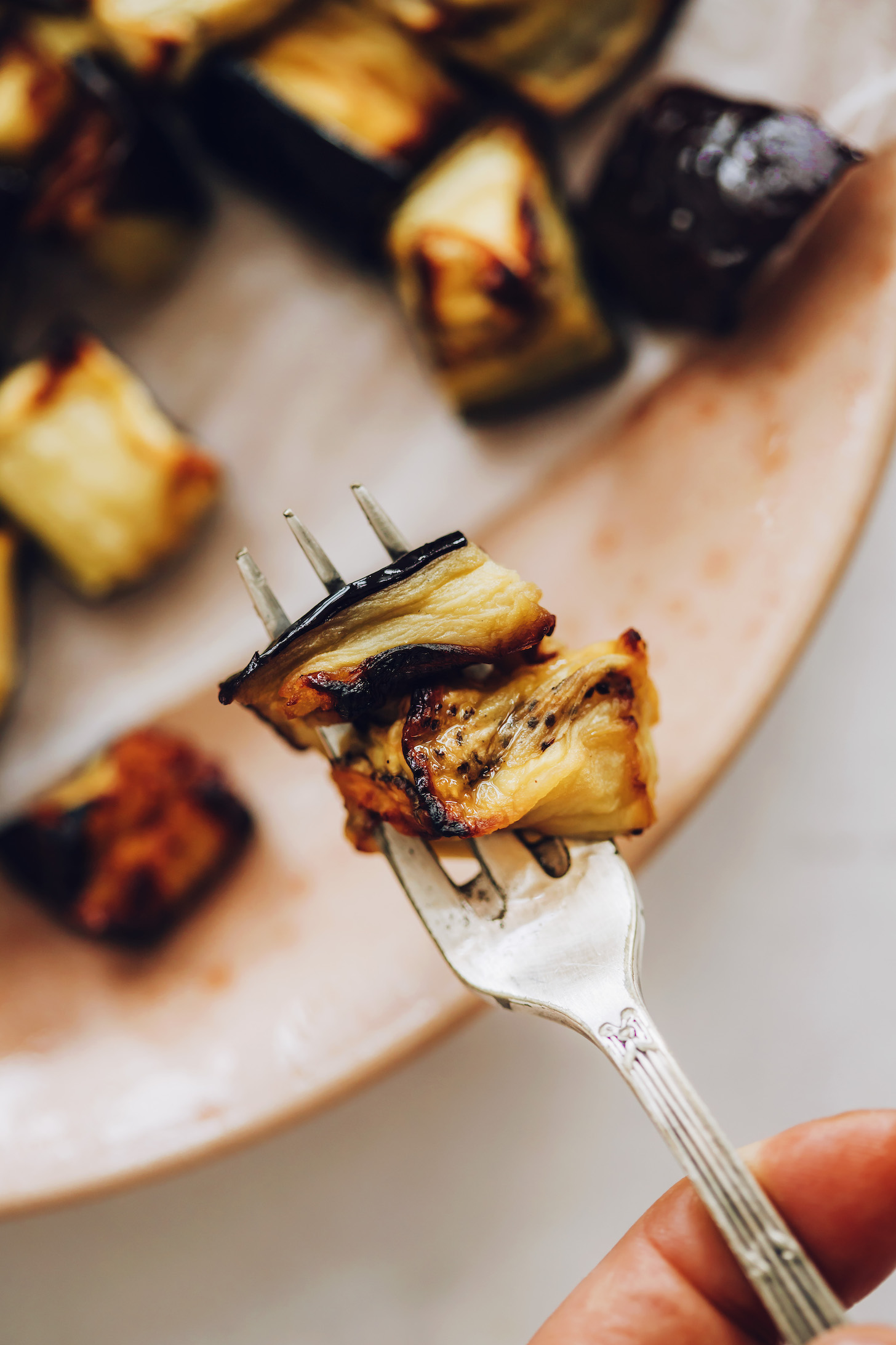 Close-up shot of a fork holding cubed roasted eggplant