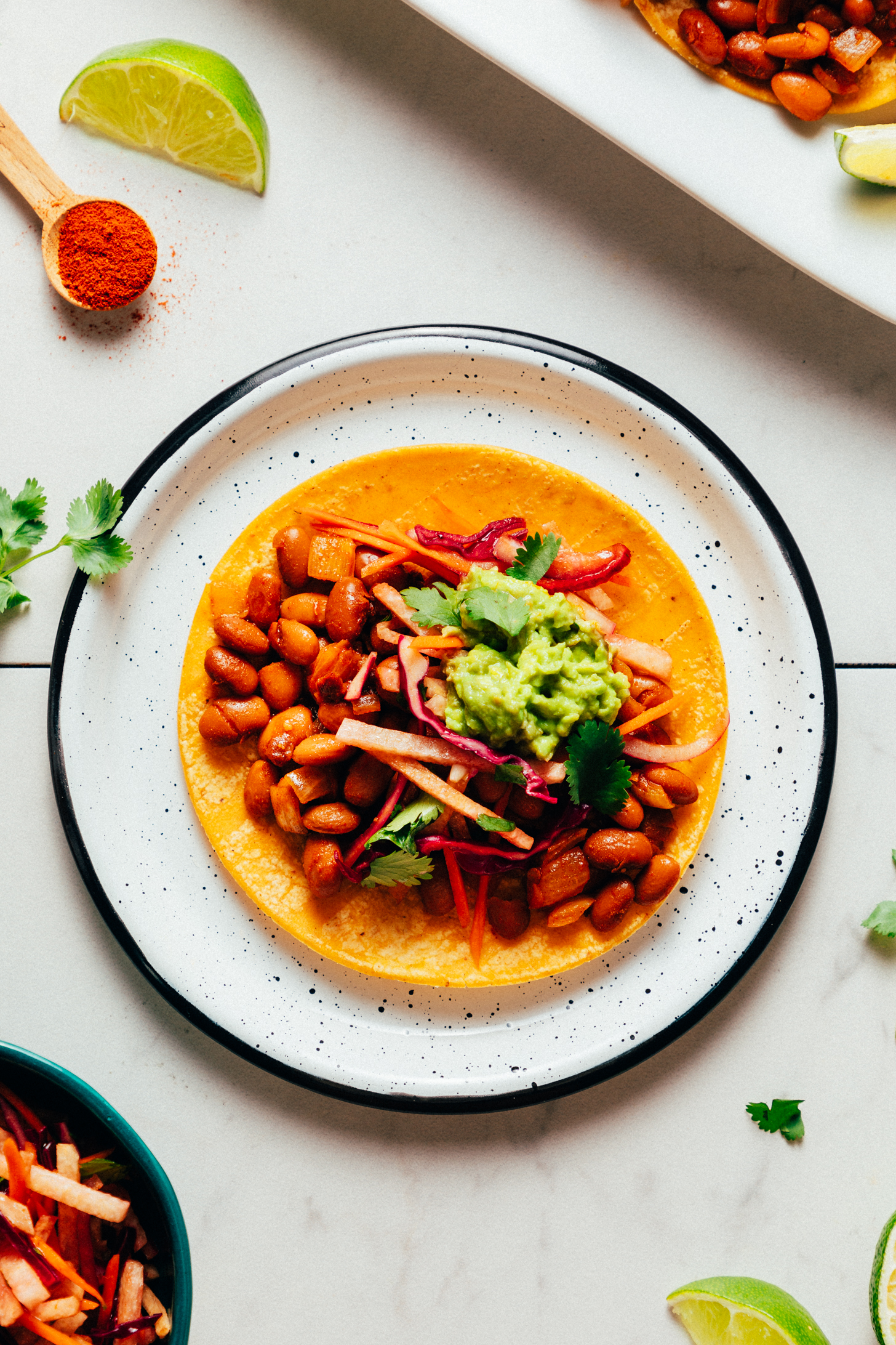 Plate with a BBQ bean vegan taco topped with jicama slaw and guacamole