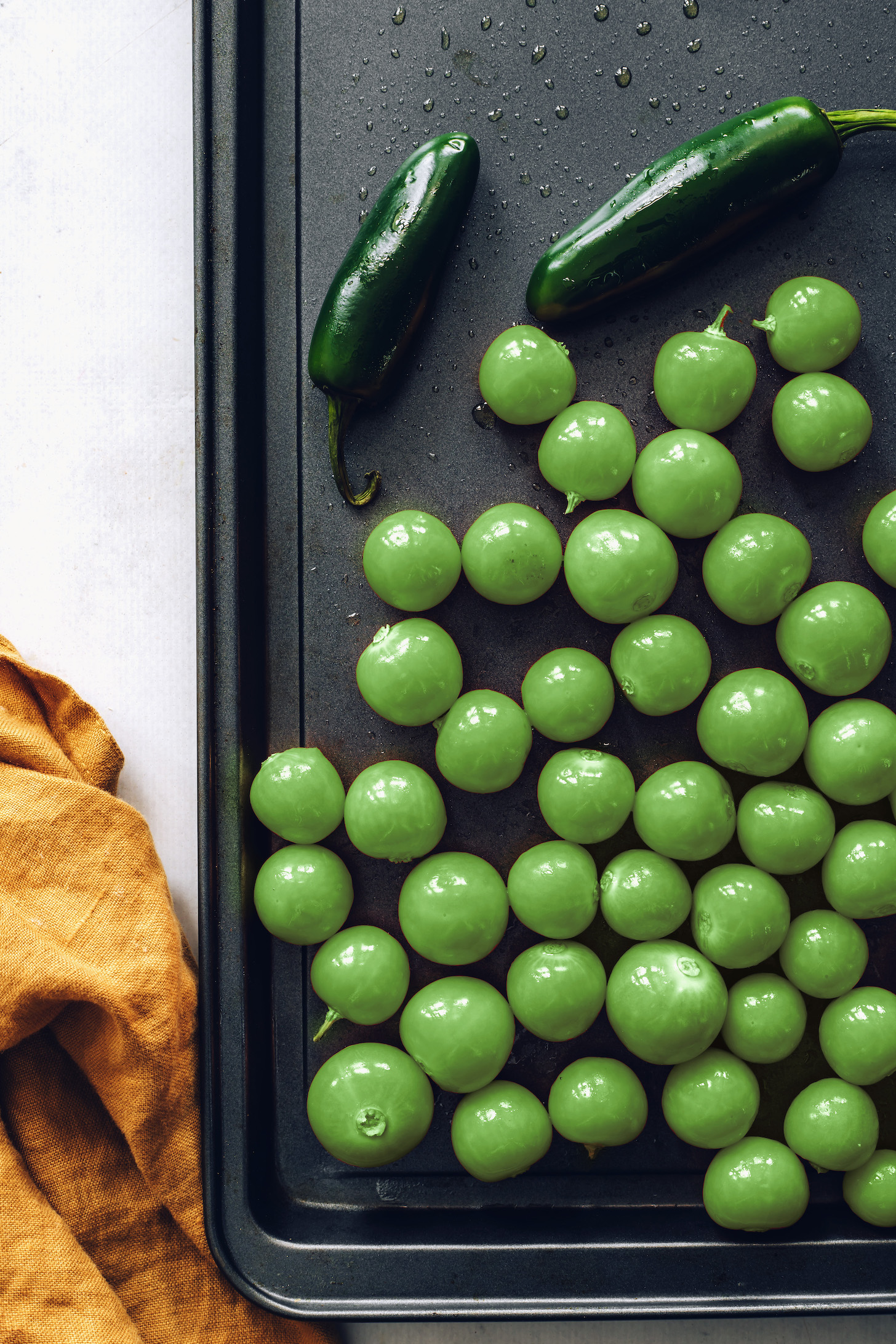 Jalapeños and tomatillos on a baking sheet