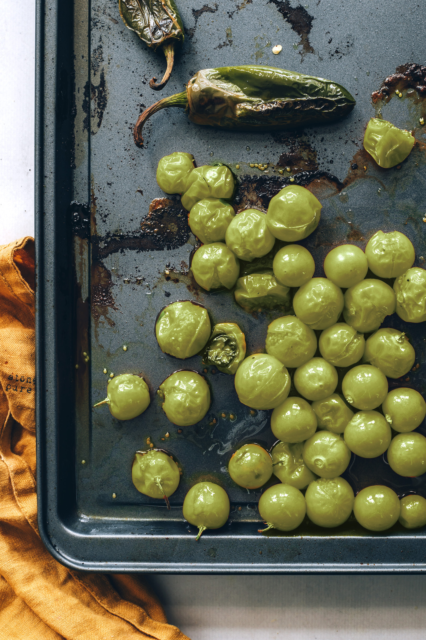 Roasted jalapeños and tomatillos on a baking sheet