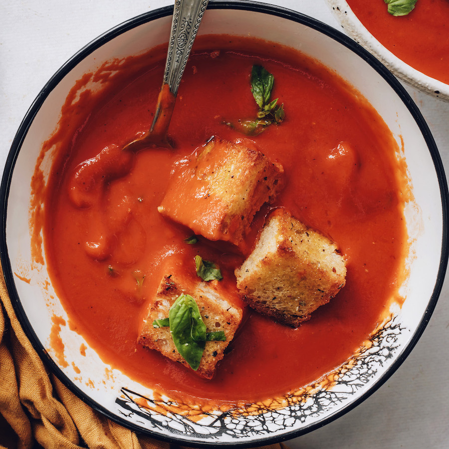 Bowl of creamy vegan tomato soup topped with croutons