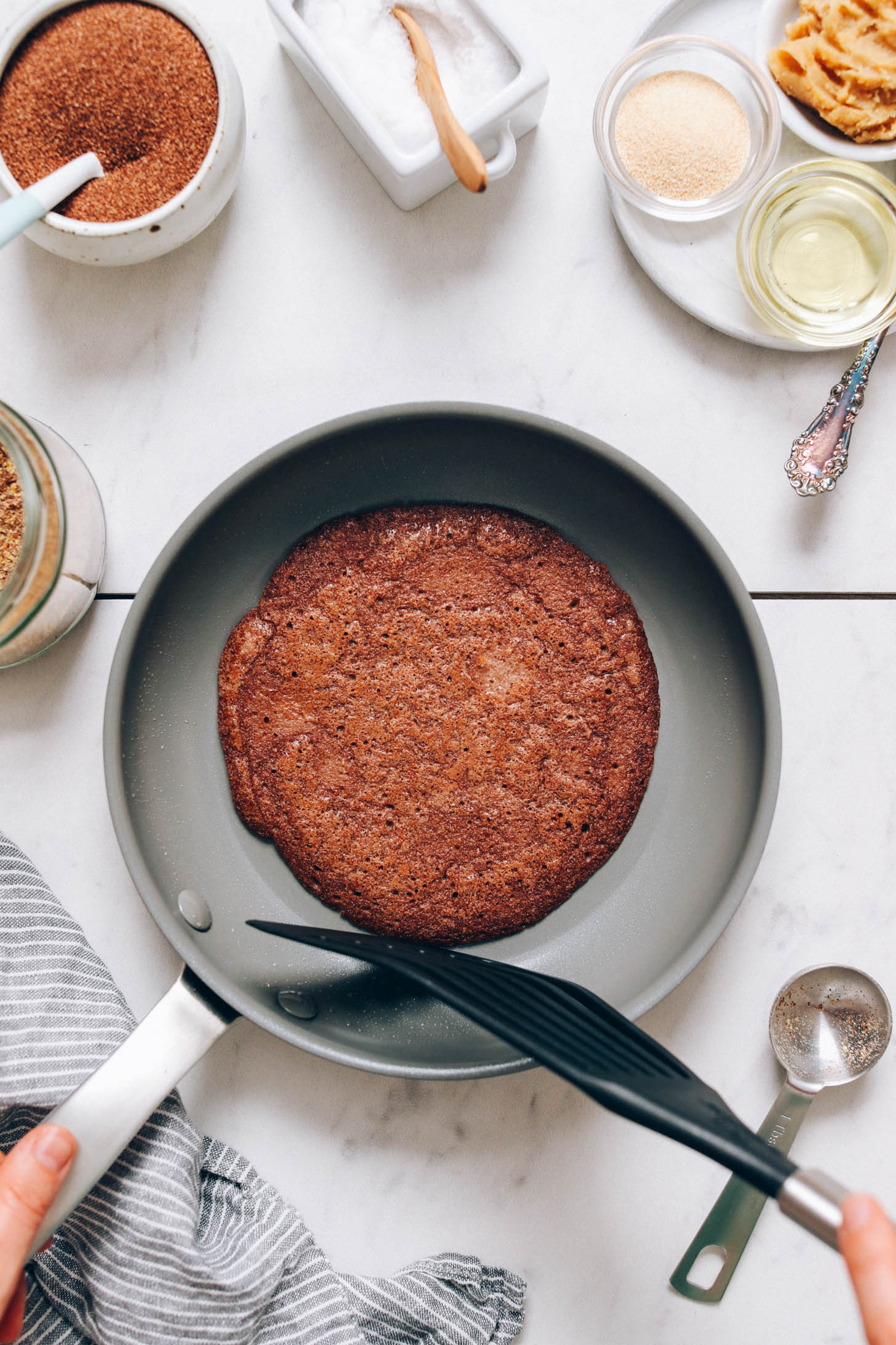 Golden brown teff crepe in a non-stick skillet
