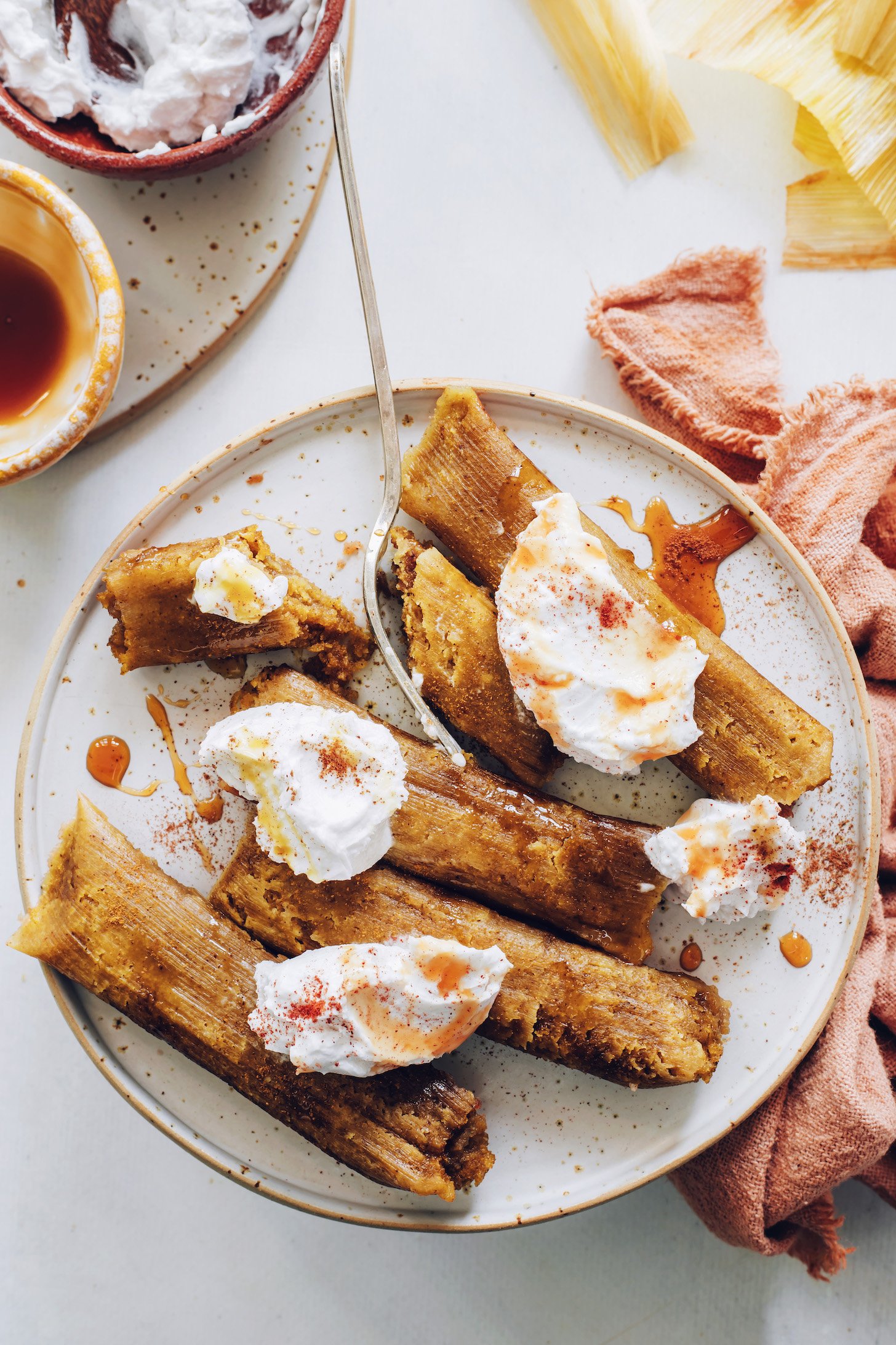 Plate of apple butter tamales drizzled with maple syrup and topped with coconut whipped cream and cinnamon