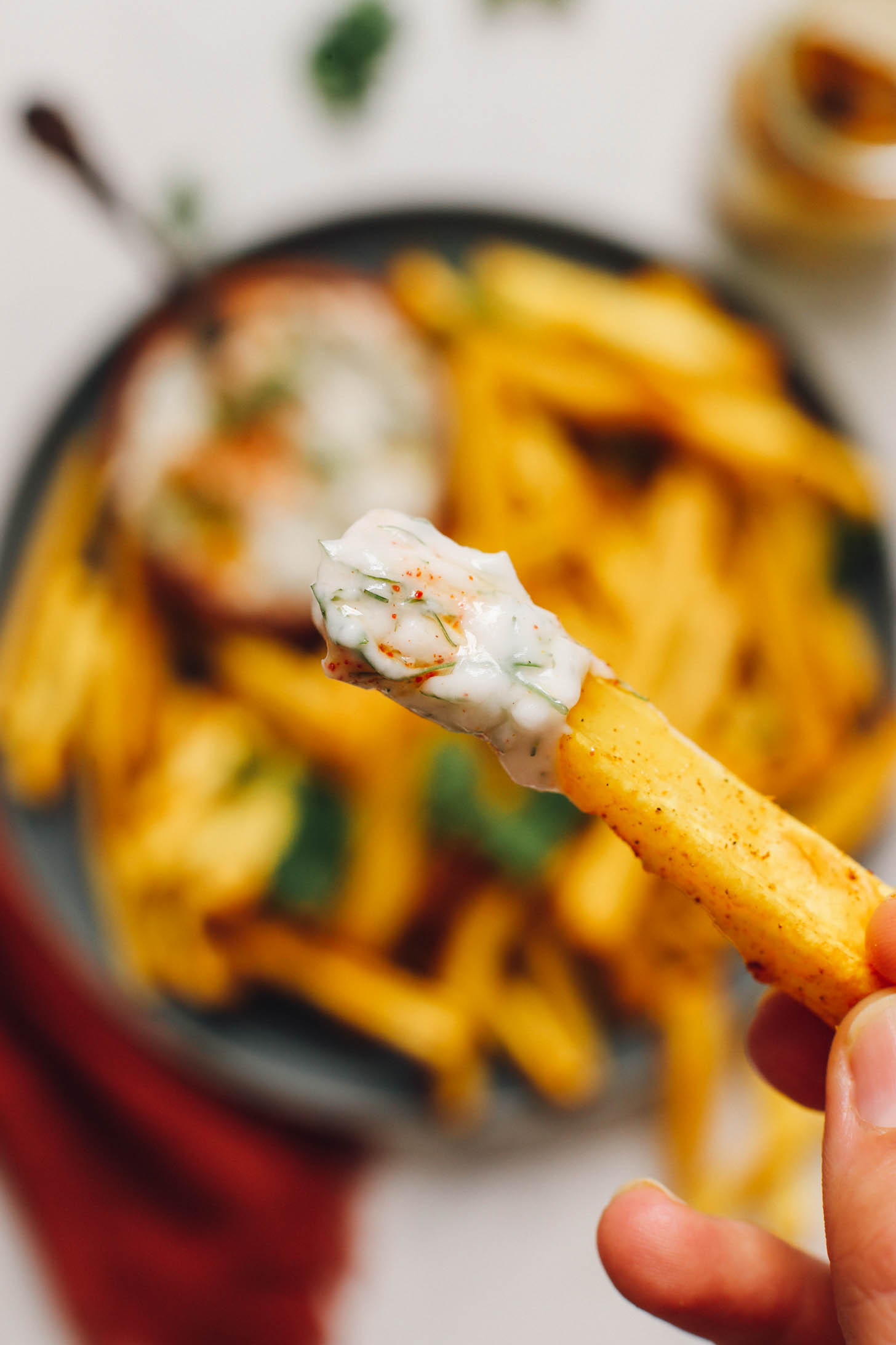 Close up shot of a curried parsnip fry dipped in yogurt dill sauce
