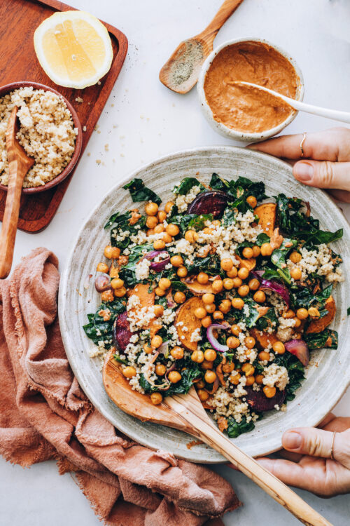 Hands holding a bowl of hearty kale salad