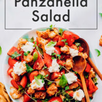Bowl of vegan heirloom tomato panzanella salad with salad tongs in it