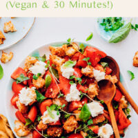 Bowl of vegan heirloom tomato panzanella salad with salad tongs in it