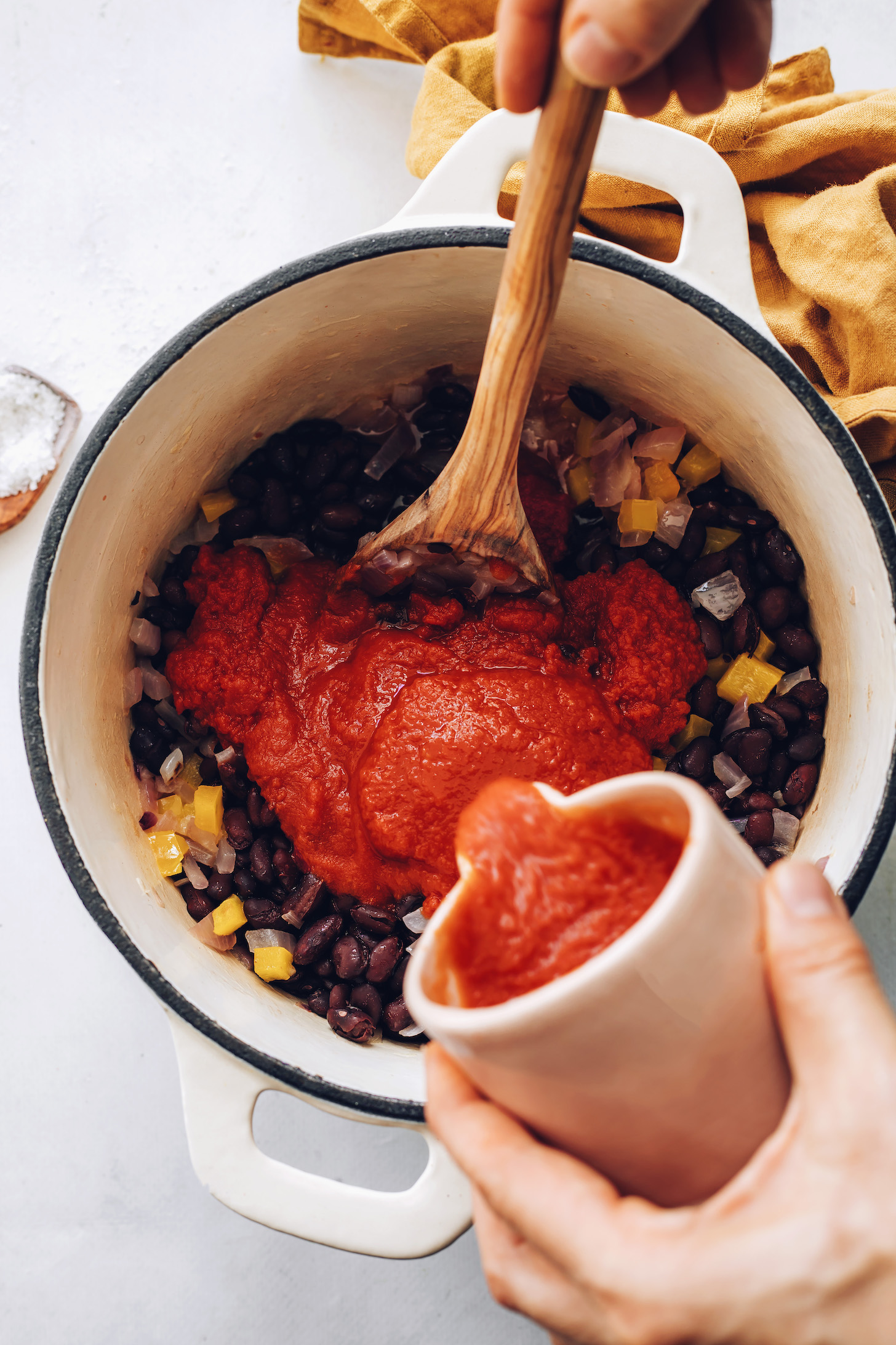 Adding enchilada sauce to sautéed onion, bell pepper, and black beans